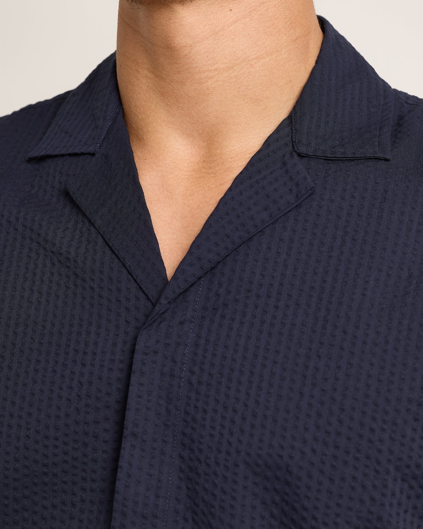 Close-up of navy short-sleeve shirt with seersucker texture on a plain background 