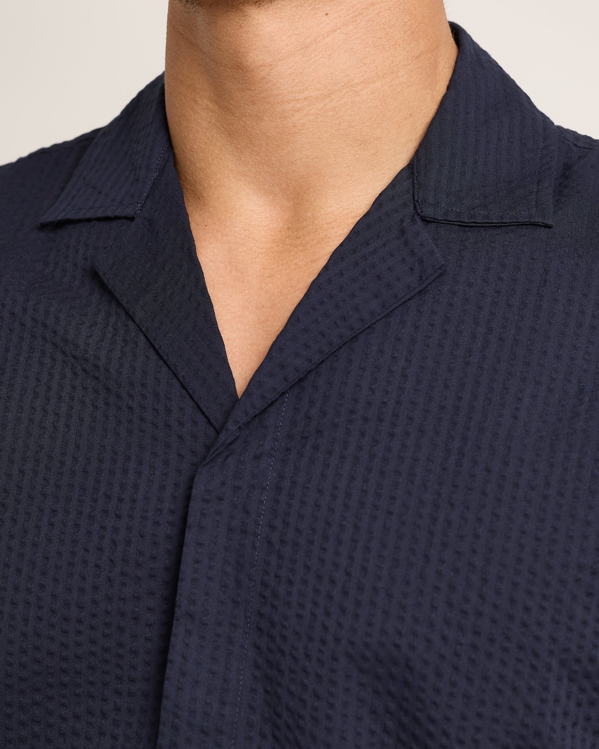 Close-up of navy short-sleeve shirt with seersucker texture on a plain background 