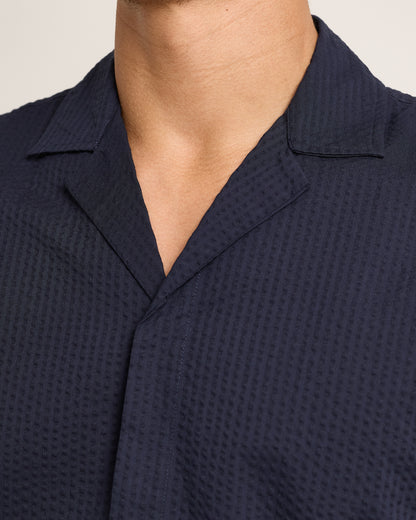 Close-up of navy short-sleeve shirt with seersucker texture on a plain background 