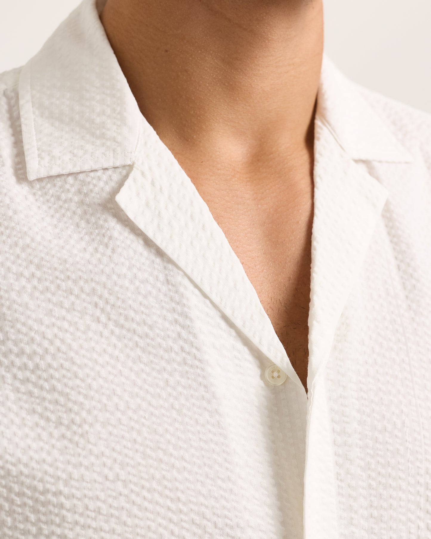 Close-up of white seersucker shirt on a plain background 