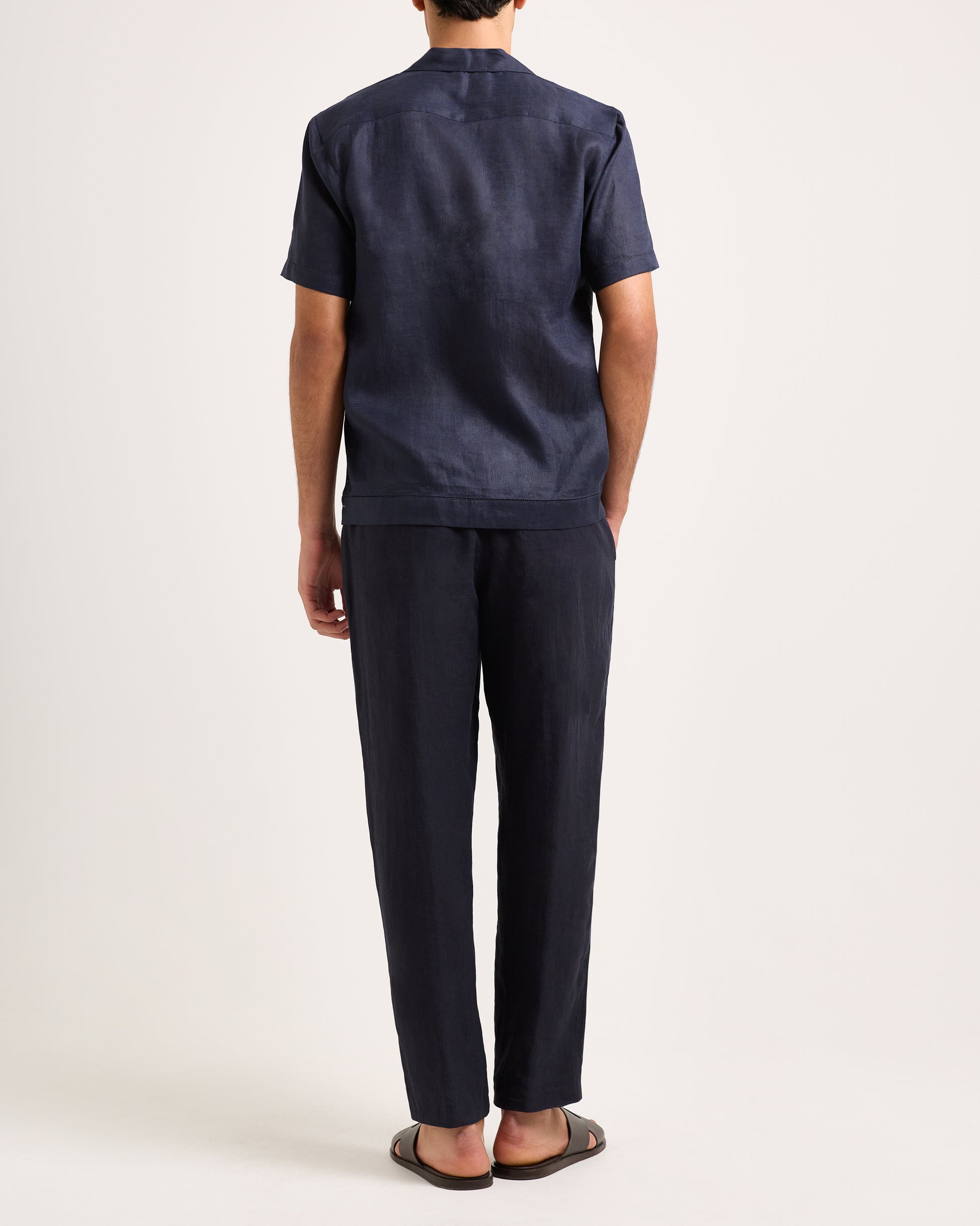 Man wearing a navy patterned shirt and pants on a white background