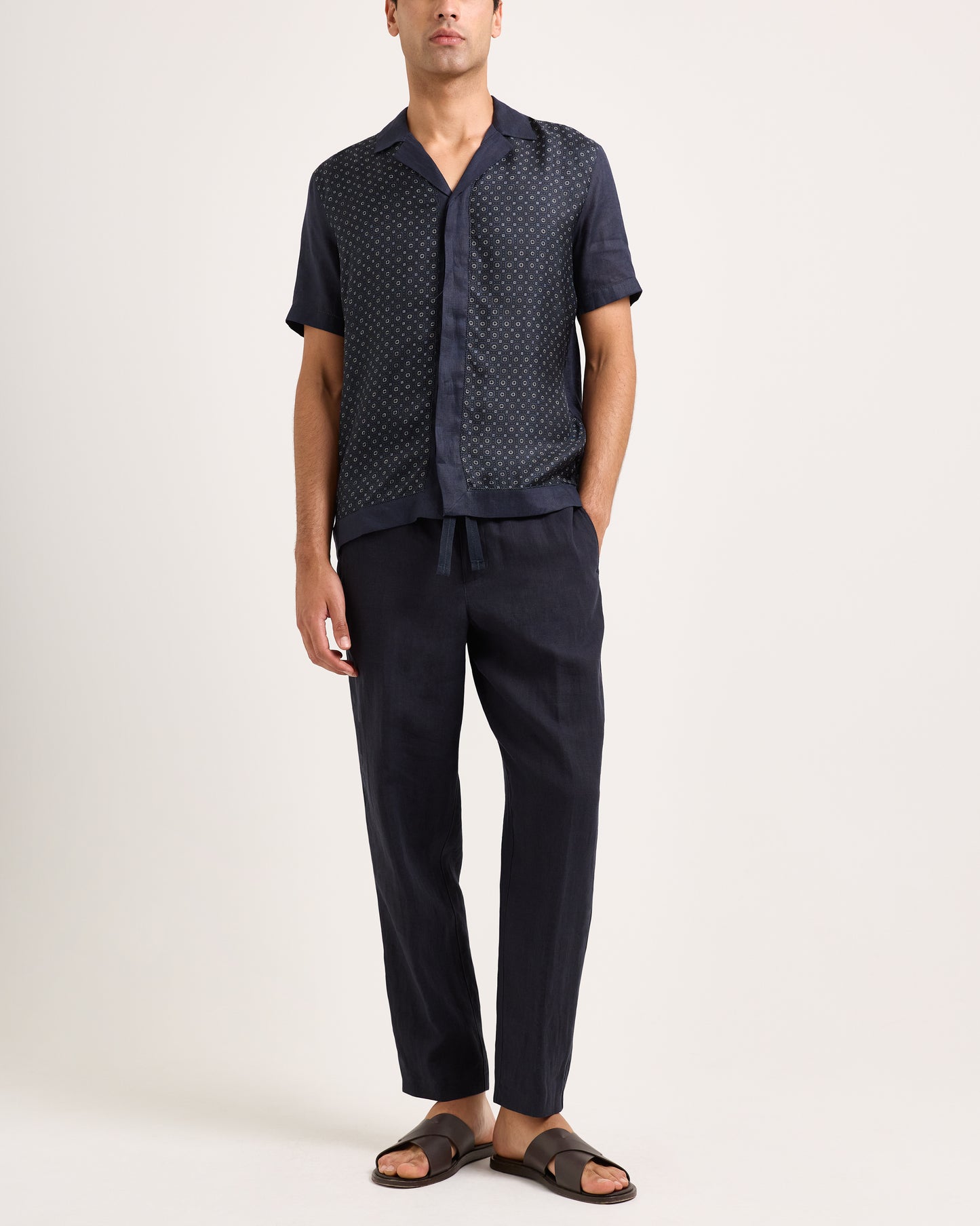 Man wearing a navy patterned shirt and pants on a white background