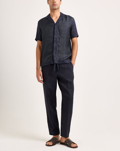 Man wearing a navy patterned shirt and pants on a white background