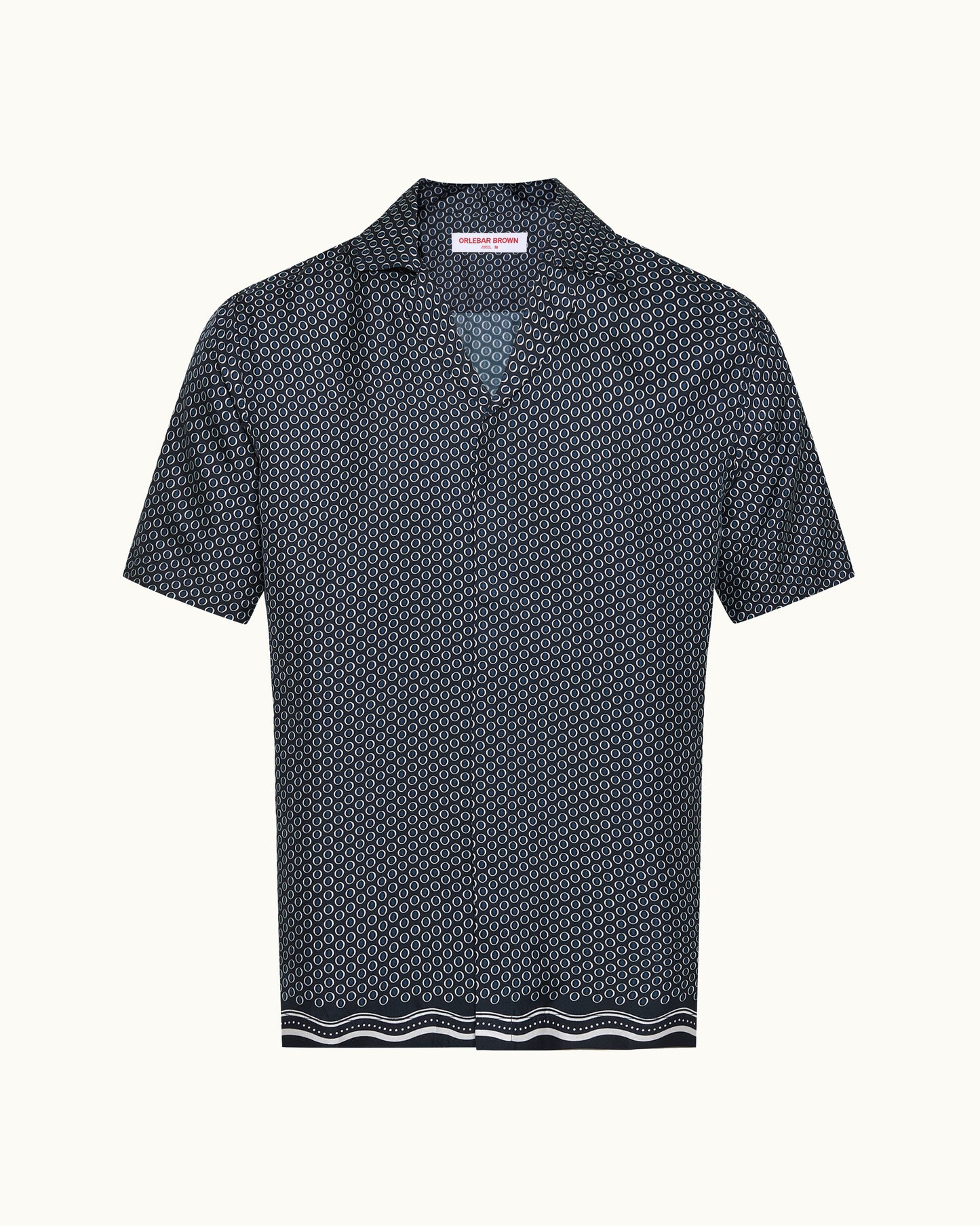 A short-sleeve collared shirt with a dense geometric micro-pattern in navy and white, featuring a striped border at the hem, shown against a plain off-white background.