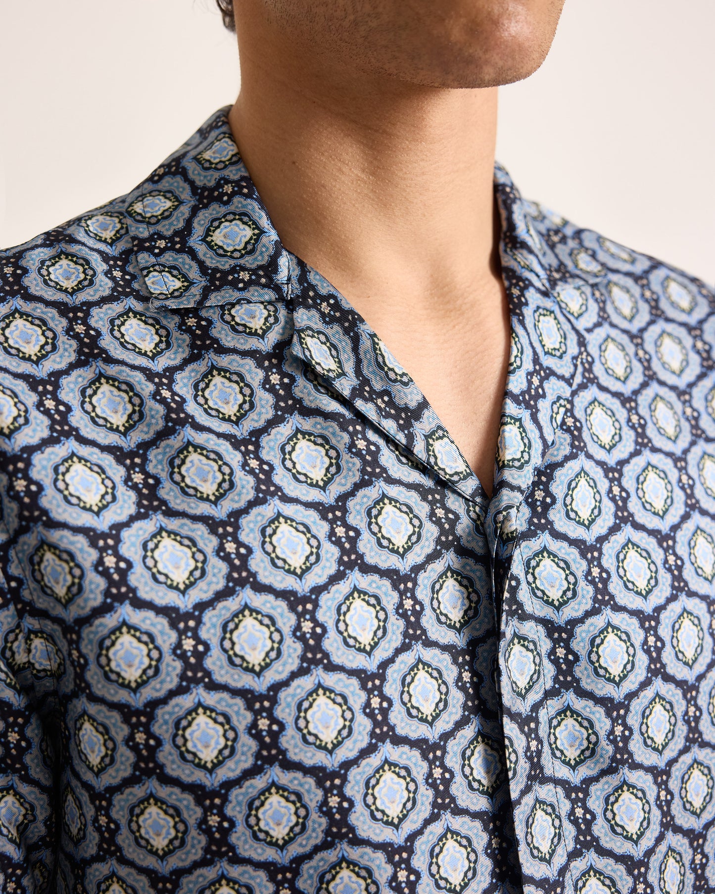 Close-up of a person wearing a patterned shirt with geometric design.