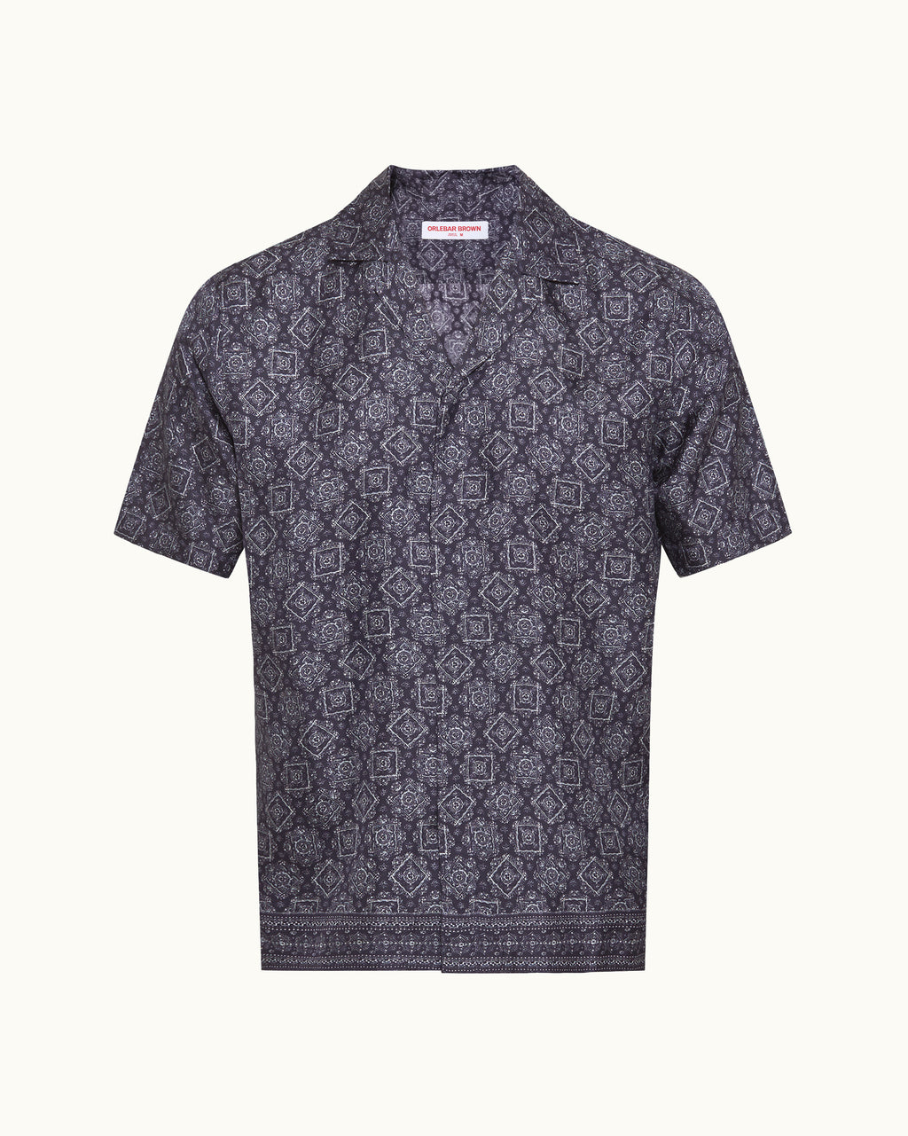 A short-sleeve button-up shirt with a dark navy and gray geometric pattern, displayed flat against a light cream background.