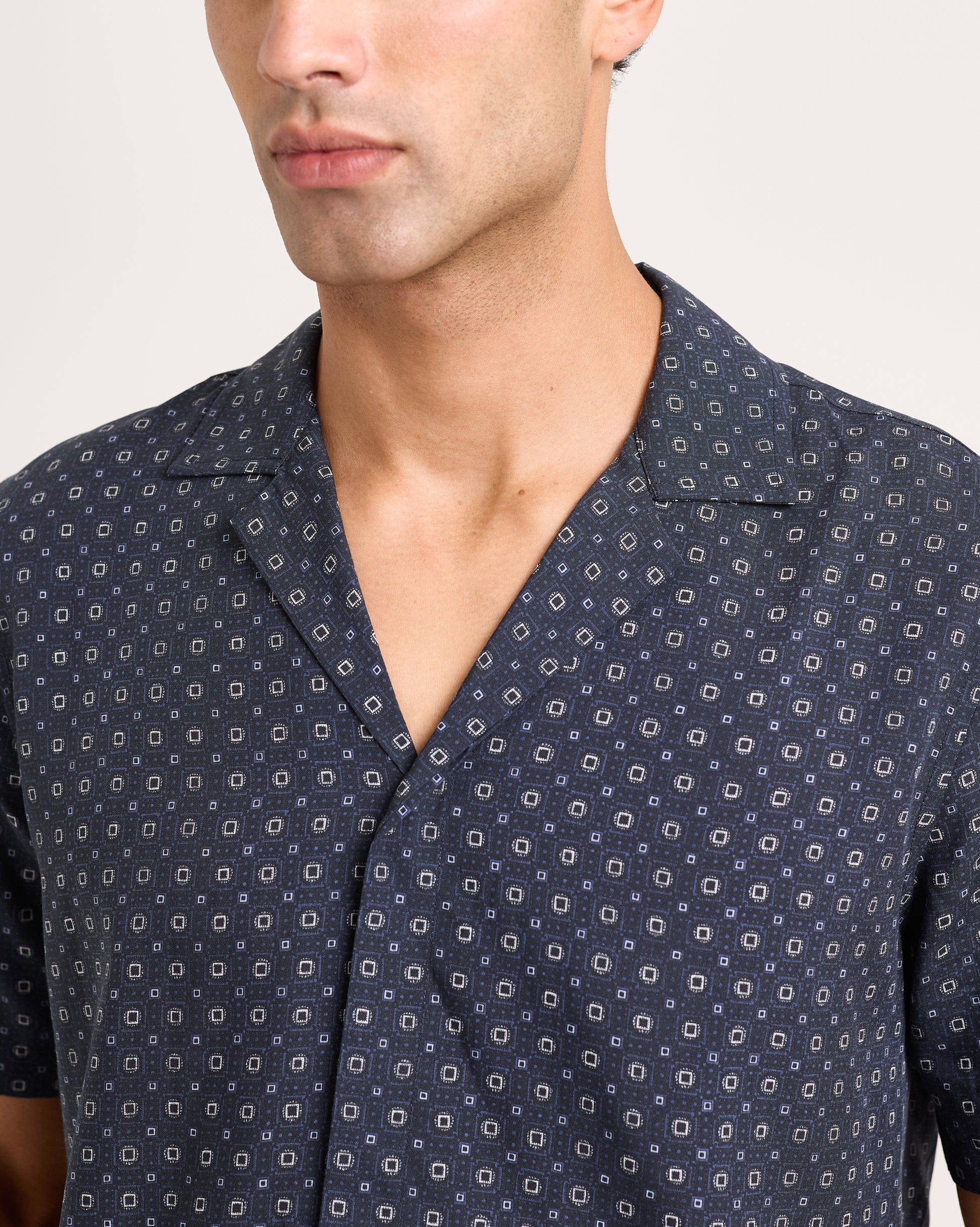 Man wearing a navy patterned shirt against a plain background