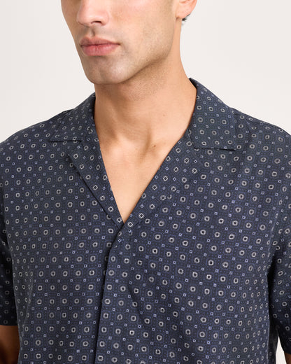 Man wearing a navy patterned shirt against a plain background