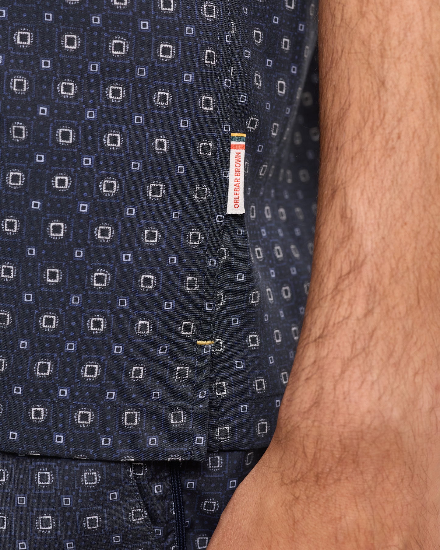 Navy patterned fabric with a visible brand label on a close-up of clothing.