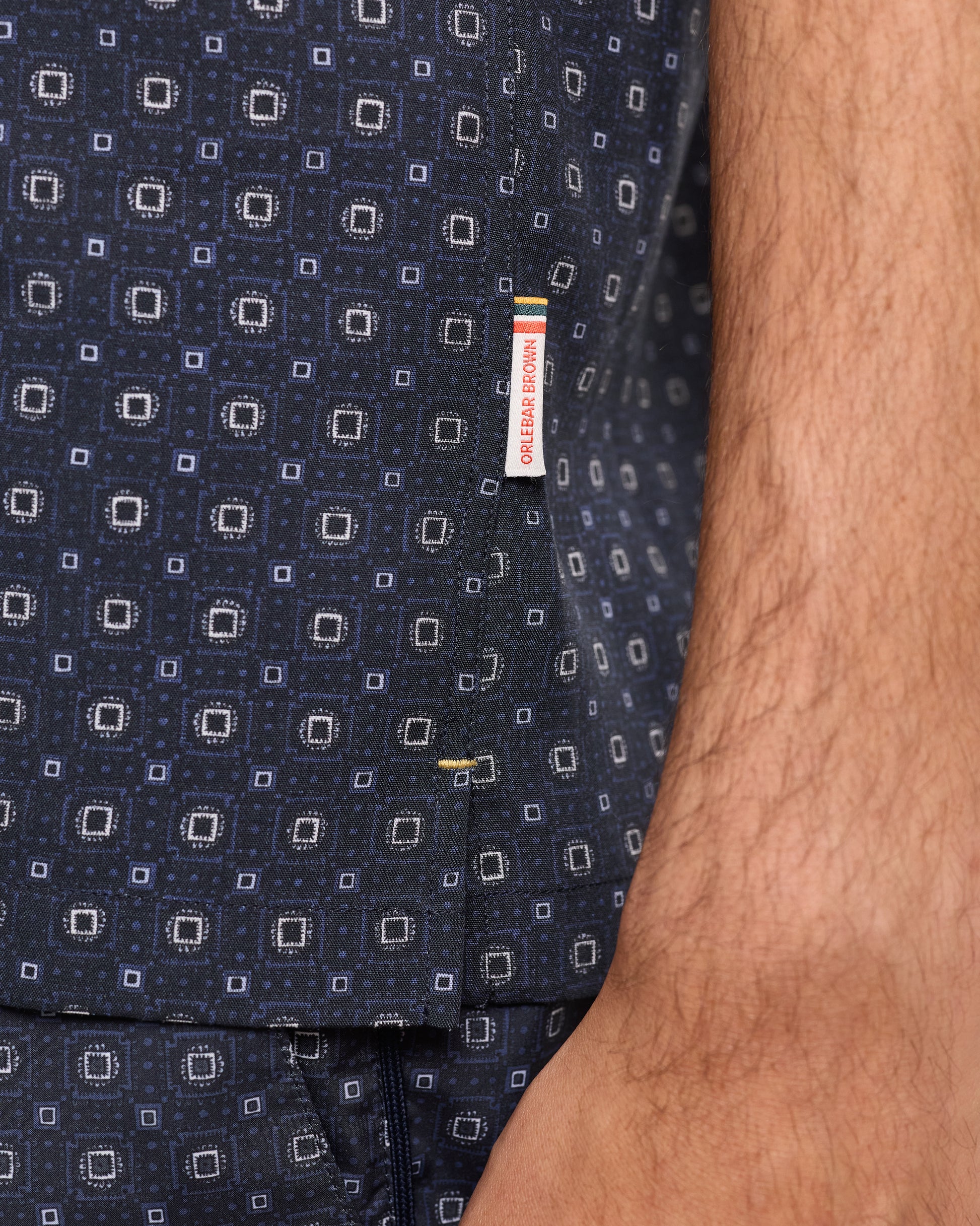 Navy patterned fabric with a visible brand label on a close-up of clothing.