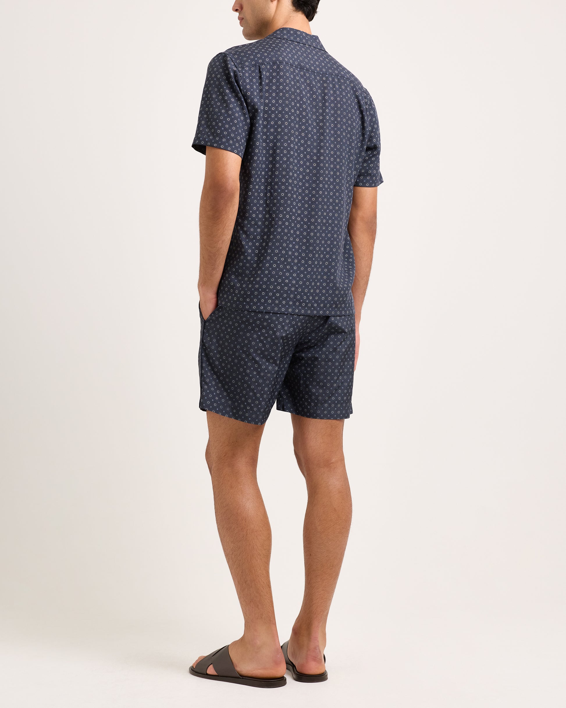 Man wearing a navy patterned shirt and shorts set on a white background