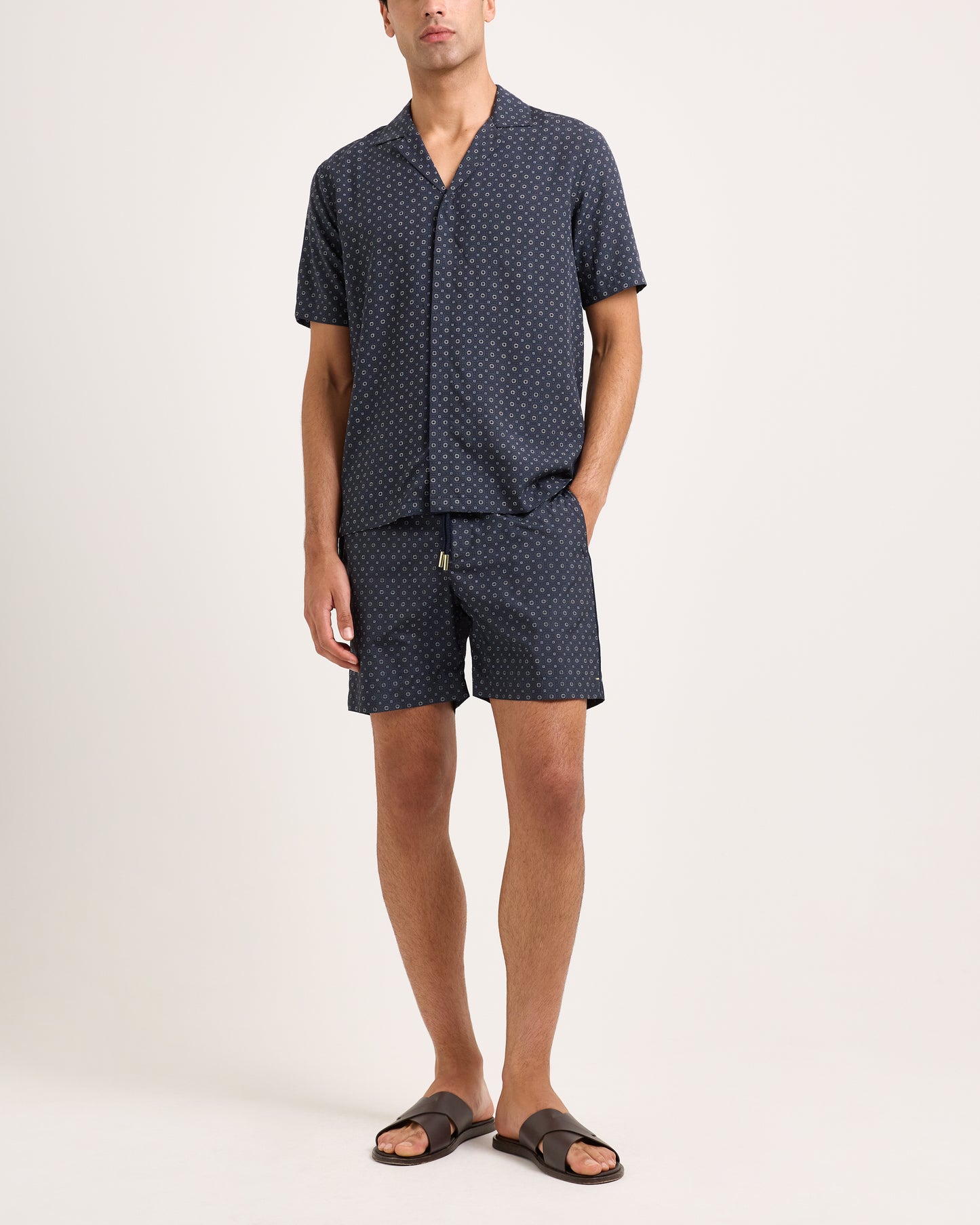 Man wearing a navy patterned shirt and shorts set on a white background