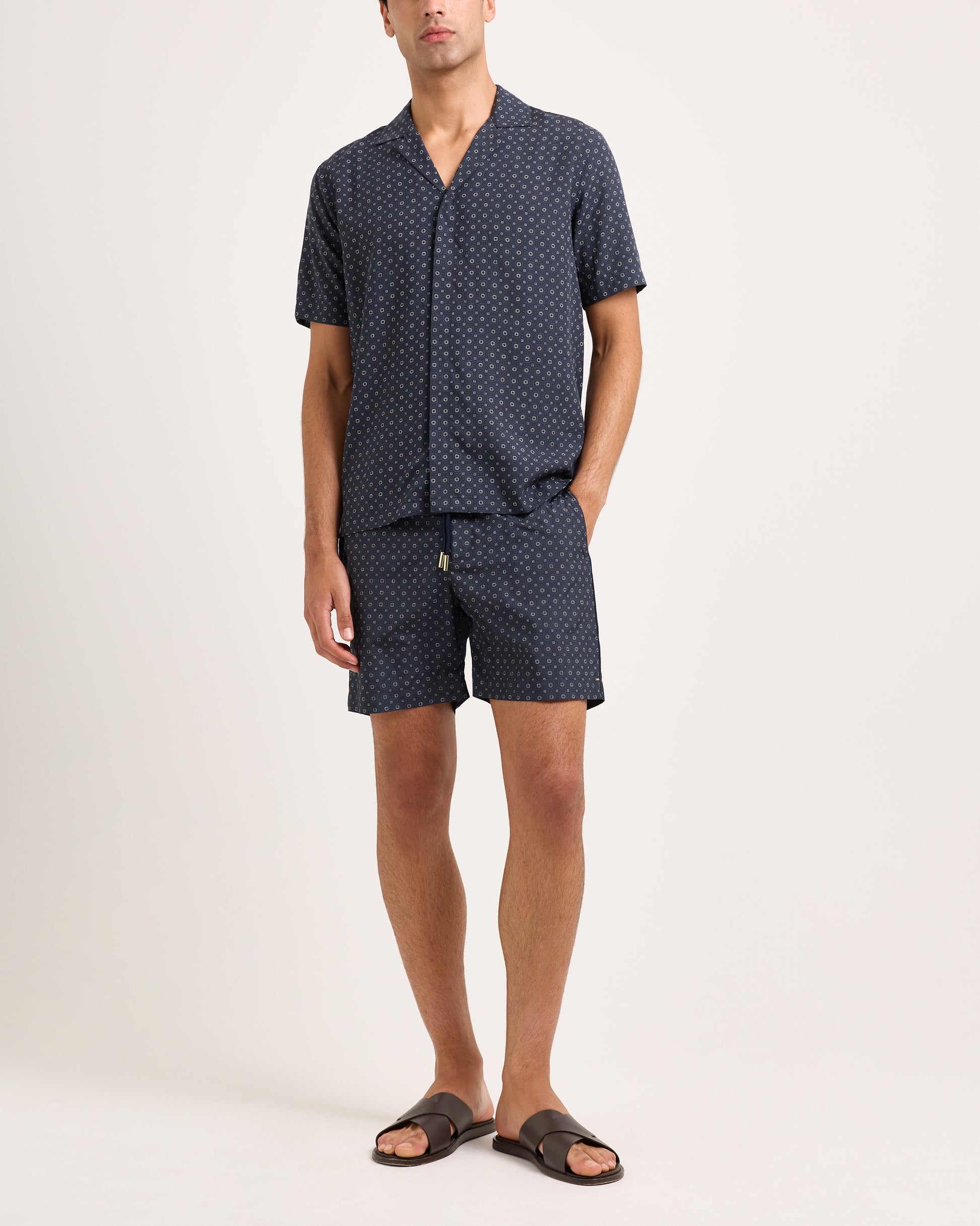 Man wearing a navy patterned shirt and shorts set on a white background