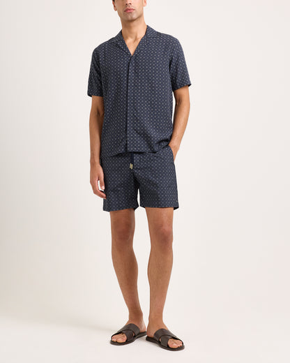 Man wearing a navy patterned shirt and shorts set on a white background