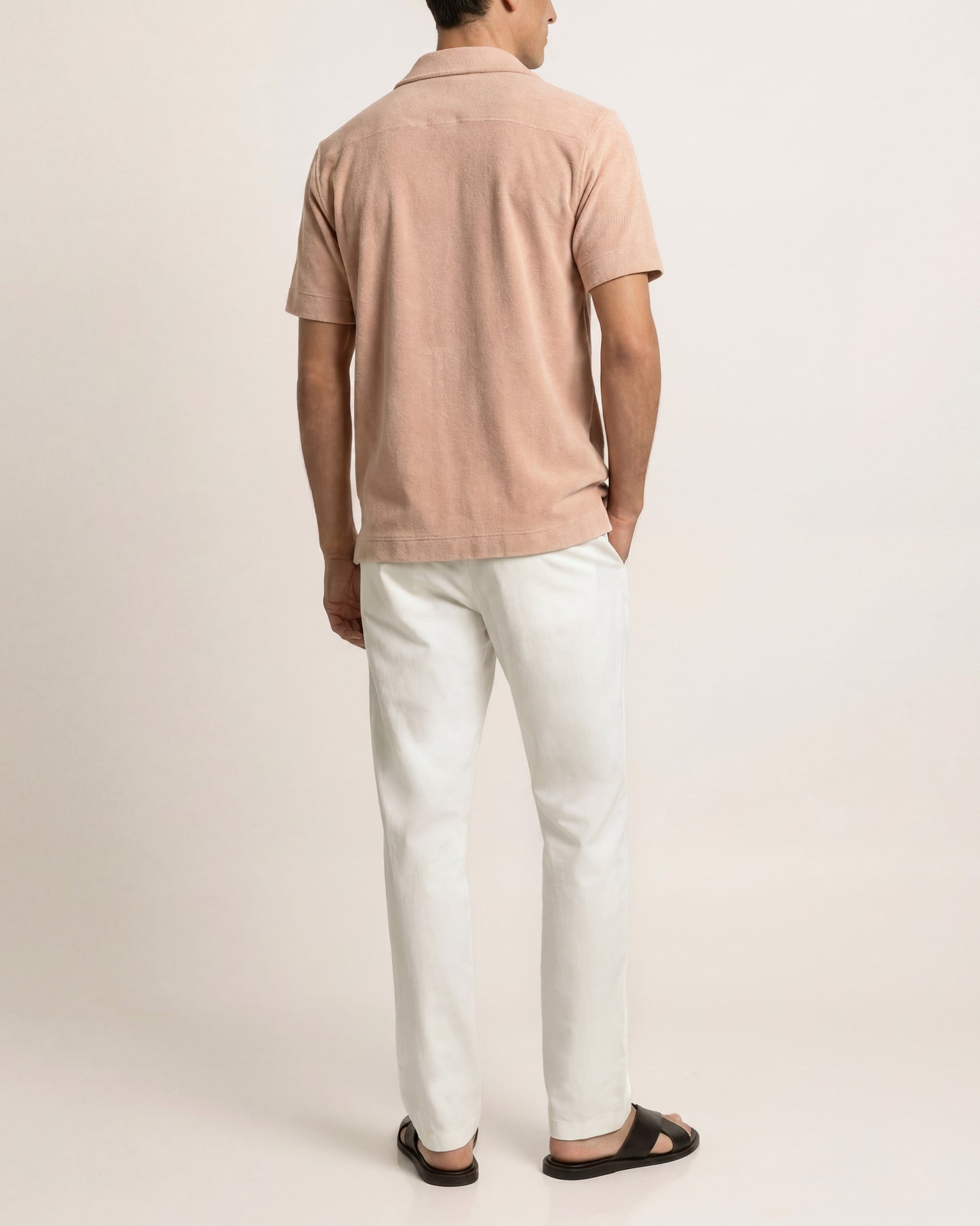 Person wearing a beige polo shirt and white pants on a light gray background