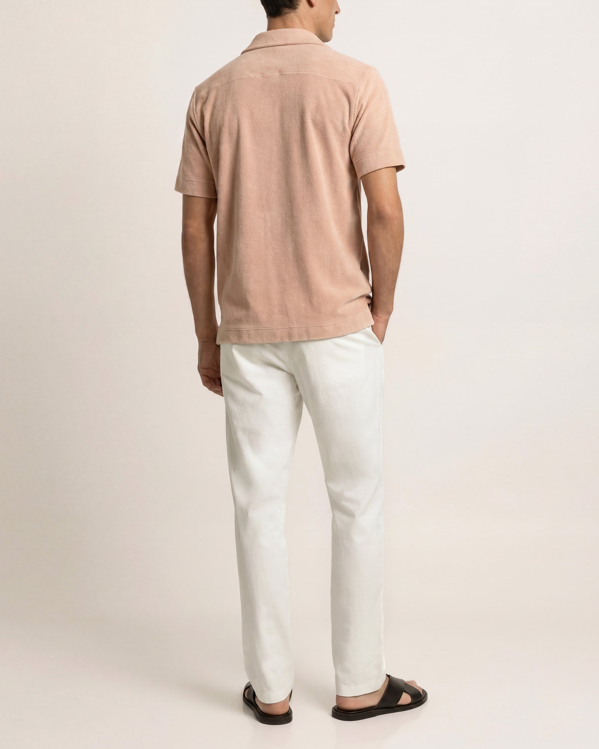 Person wearing a beige polo shirt and white pants on a light gray background