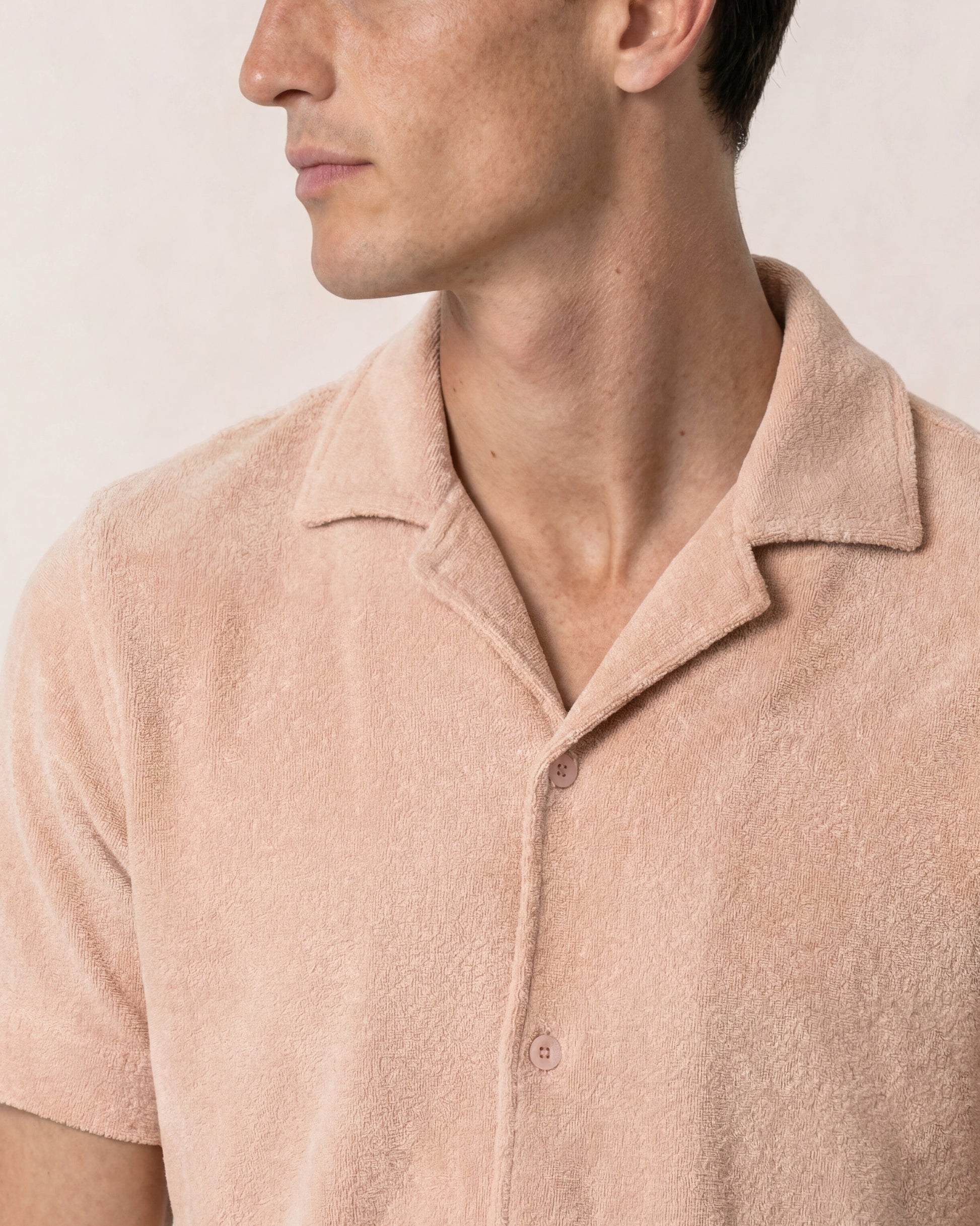 Close-up of a person wearing a beige polo shirt against a plain background