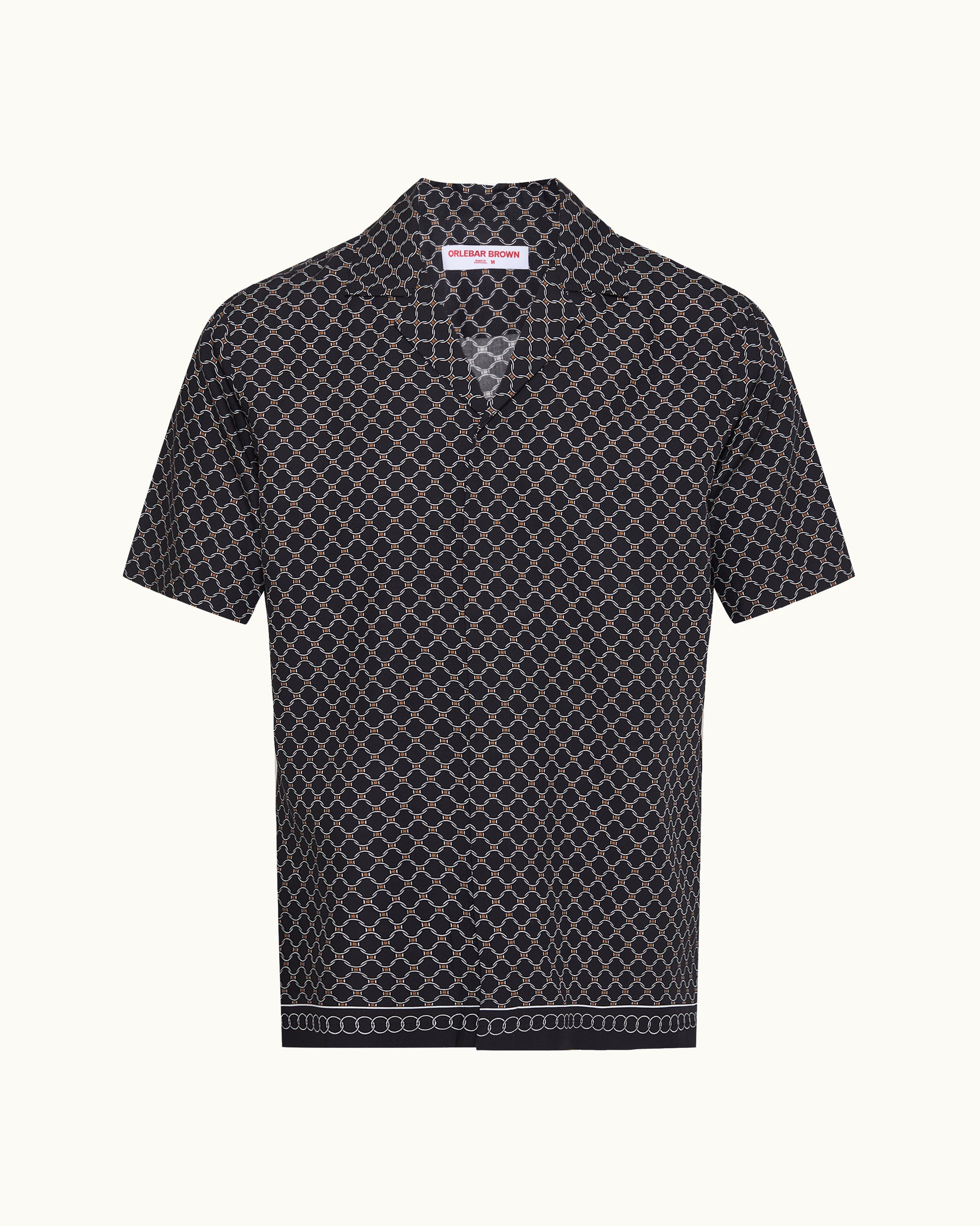 A short-sleeve button-up shirt with a black base and a white geometric lattice pattern, featuring a pointed collar and a decorative border on the hem, shown against a plain off-white background.