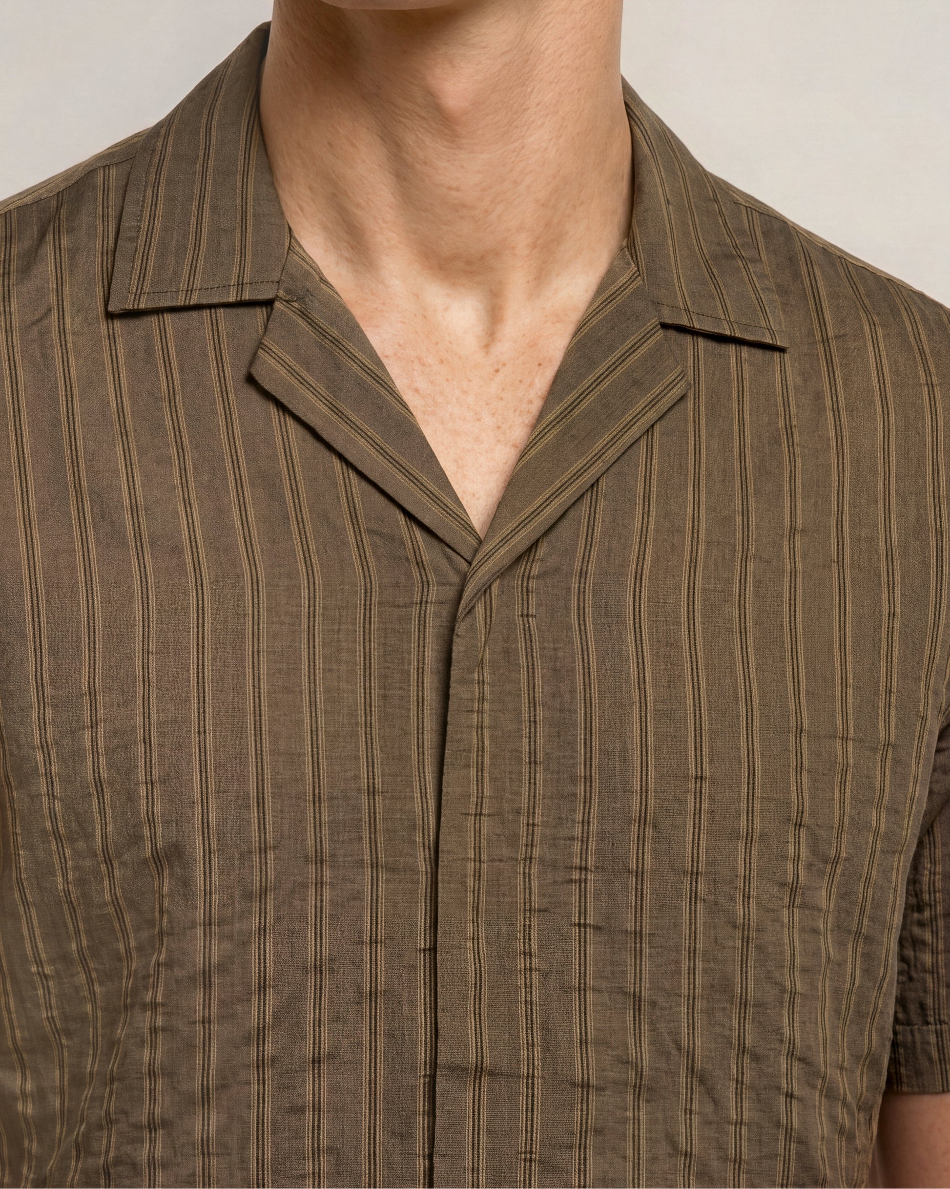 Brown pinstripe shirt worn by a person on a neutral background