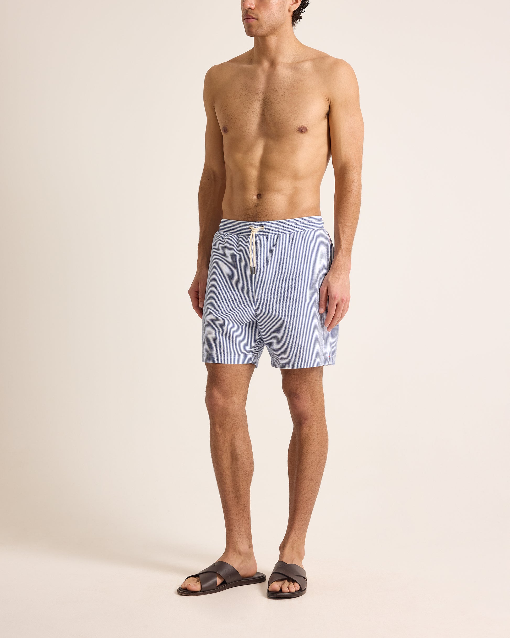 Man wearing light blue swim shorts on a beige background