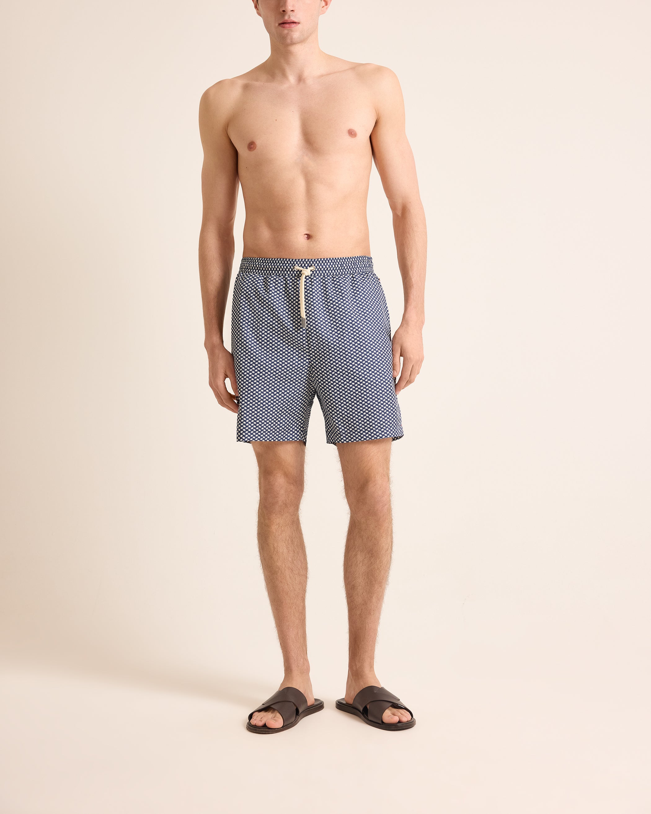 Man wearing blue patterned swim shorts on a beige background