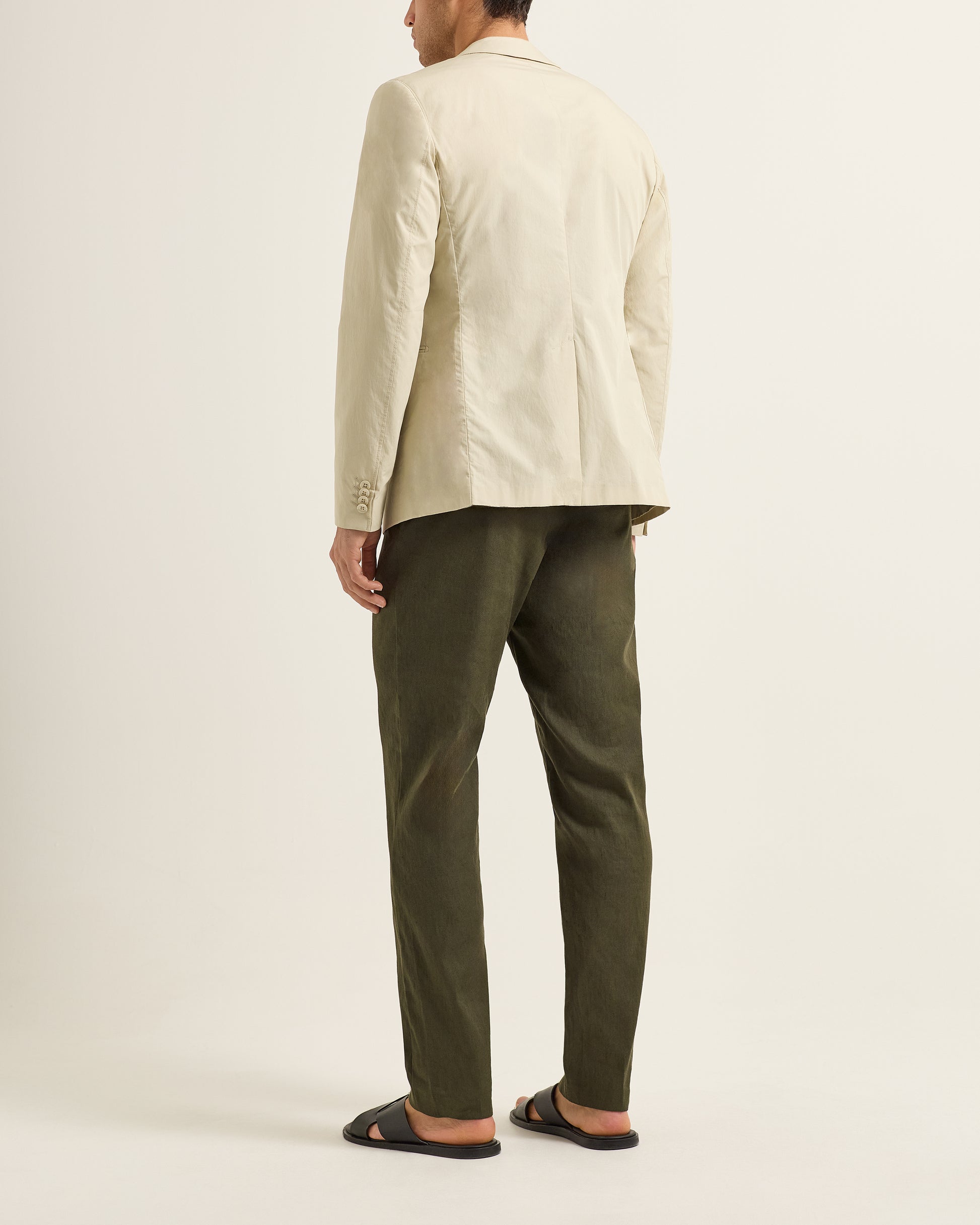 Person wearing a beige blazer and green pants on a plain background