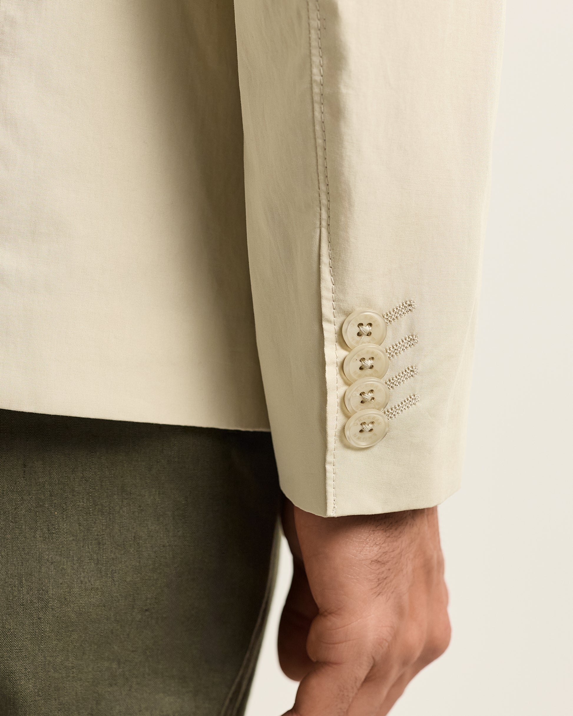 Close-up of a beige suit jacket with buttons on a white background