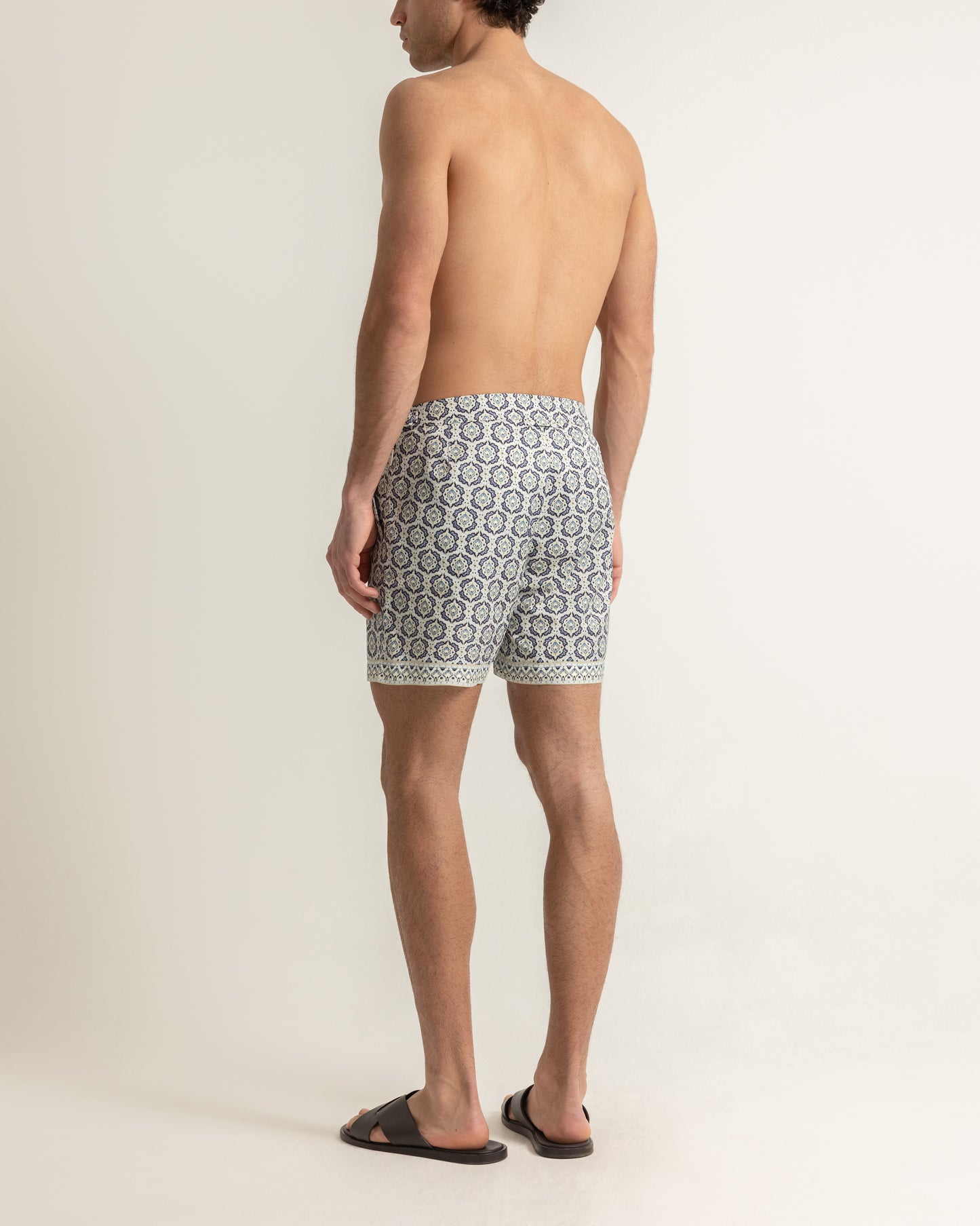 Man wearing patterned swim shorts on a plain background