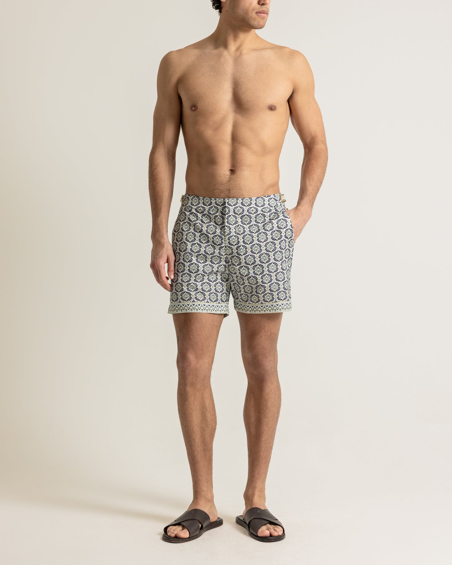 Man wearing patterned swim shorts on a plain background