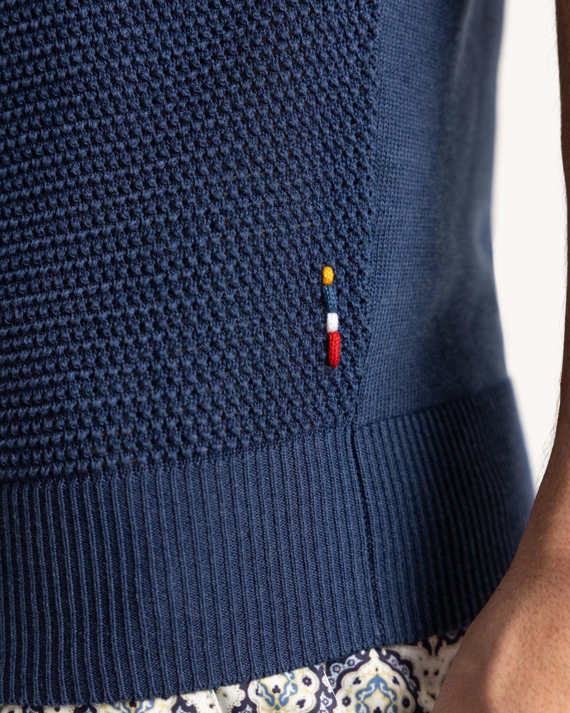 Closeup of navy knitted polo shirt with branded embroidery