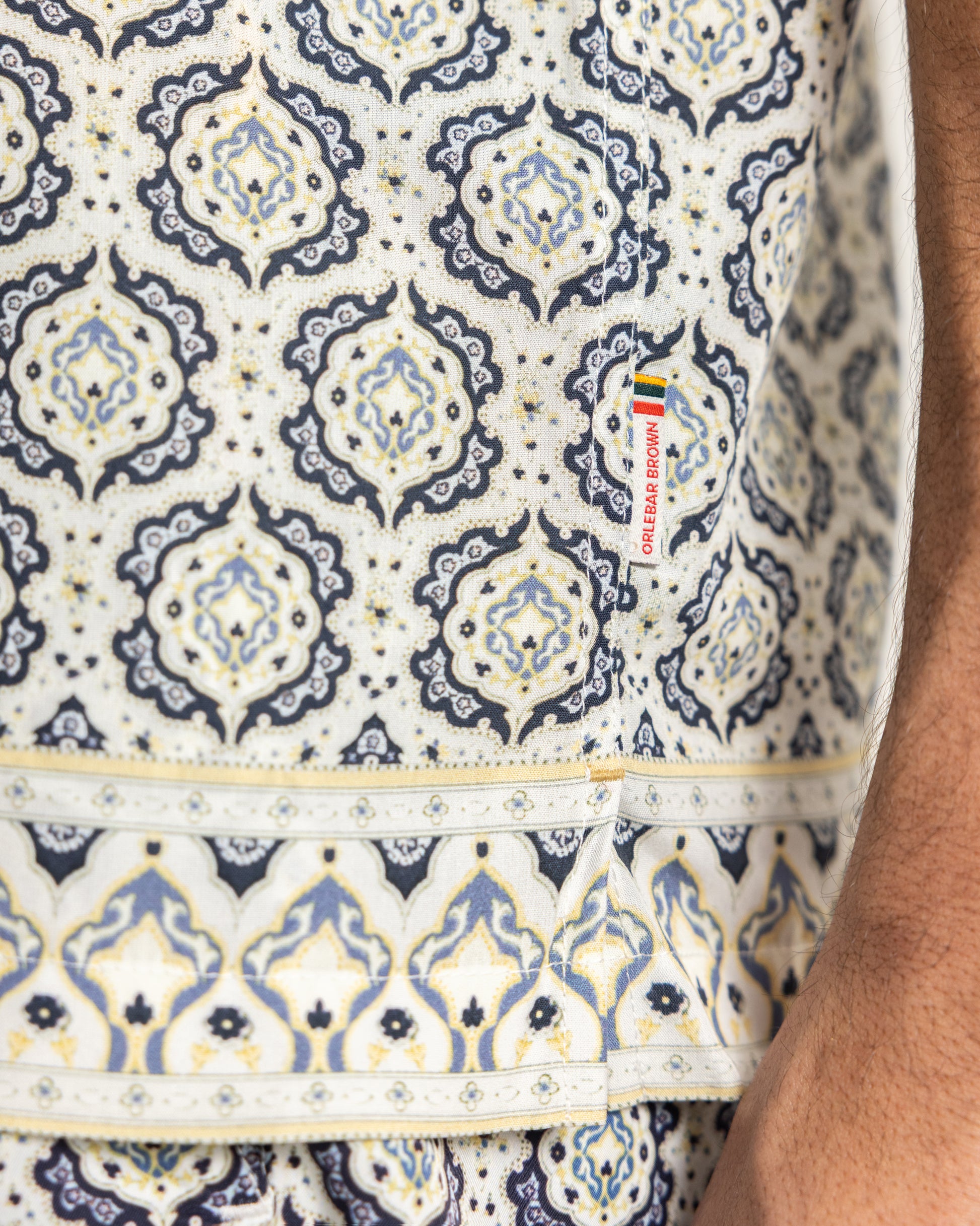 Closeup of beige printed shirt with brand logo 