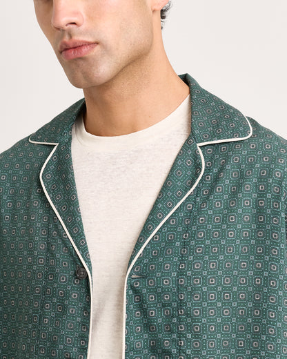 Close-up of green patterned jacket with white piping on a white background