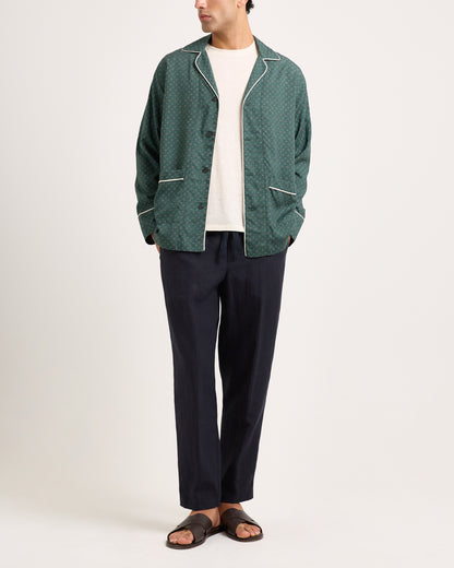 Person wearing a green patterned jacket and dark pants on a white background