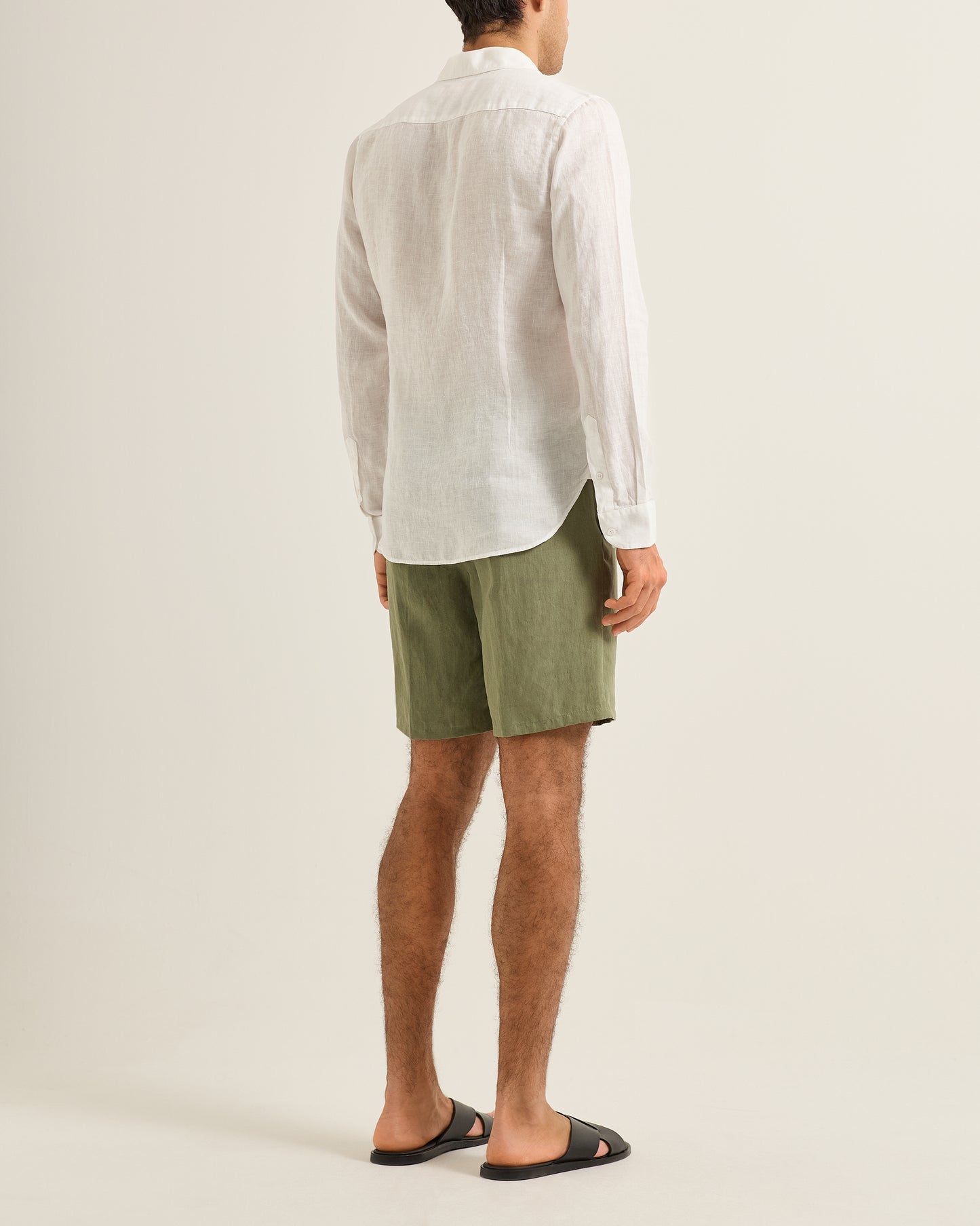 Person wearing a white shirt and green shorts on a beige background