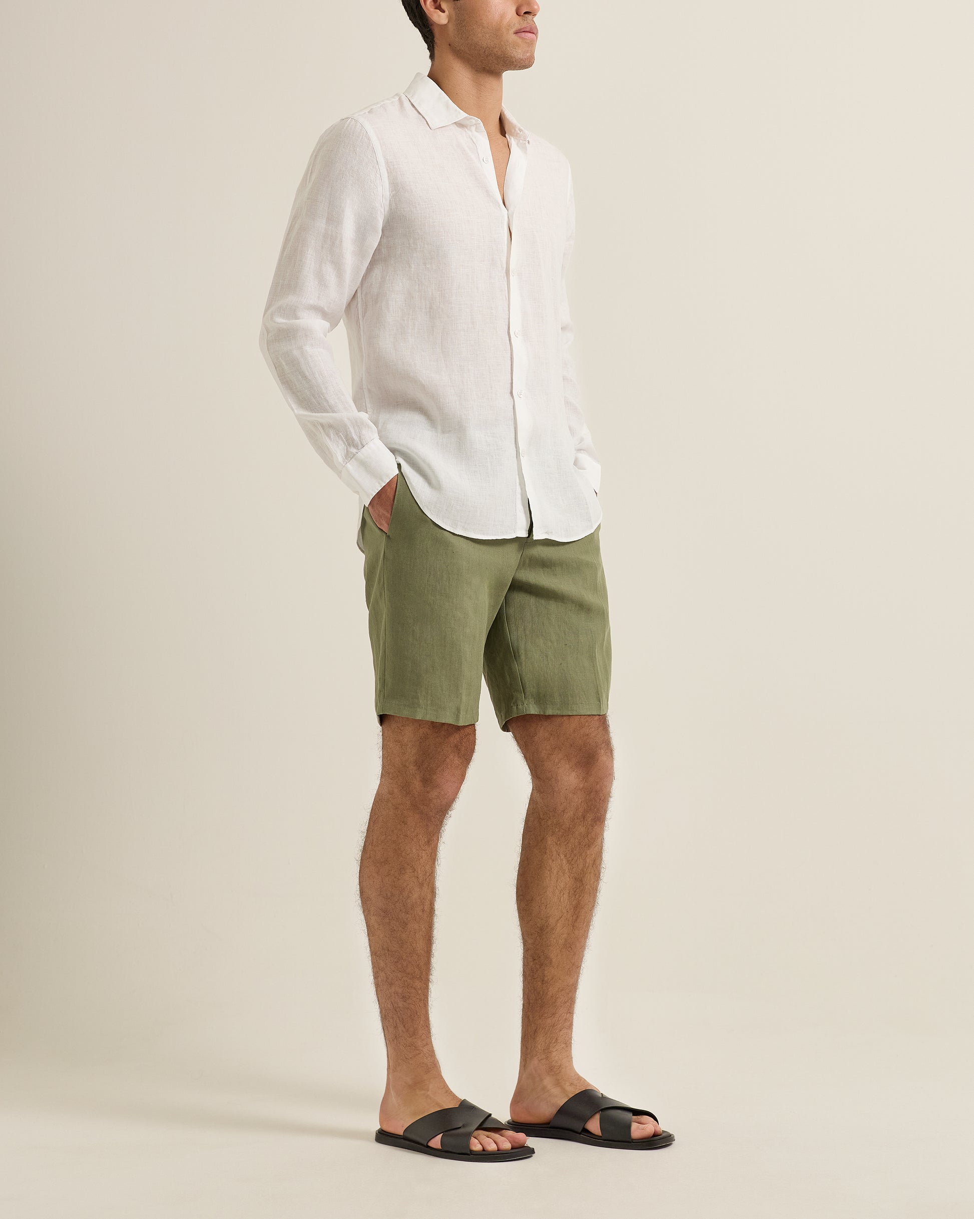 Man wearing a white shirt and green shorts on a beige background