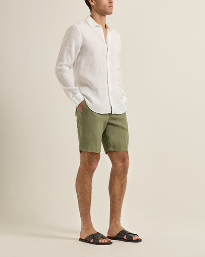 Man wearing a white shirt and green shorts on a beige background