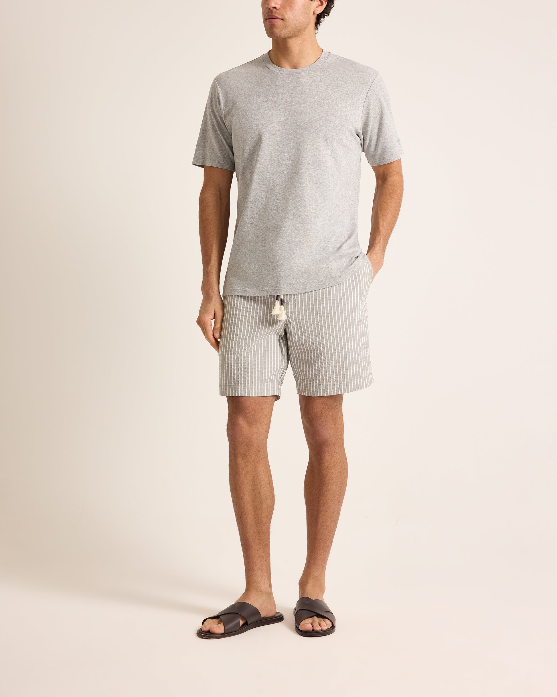 Man wearing a gray t-shirt and shorts on a beige background