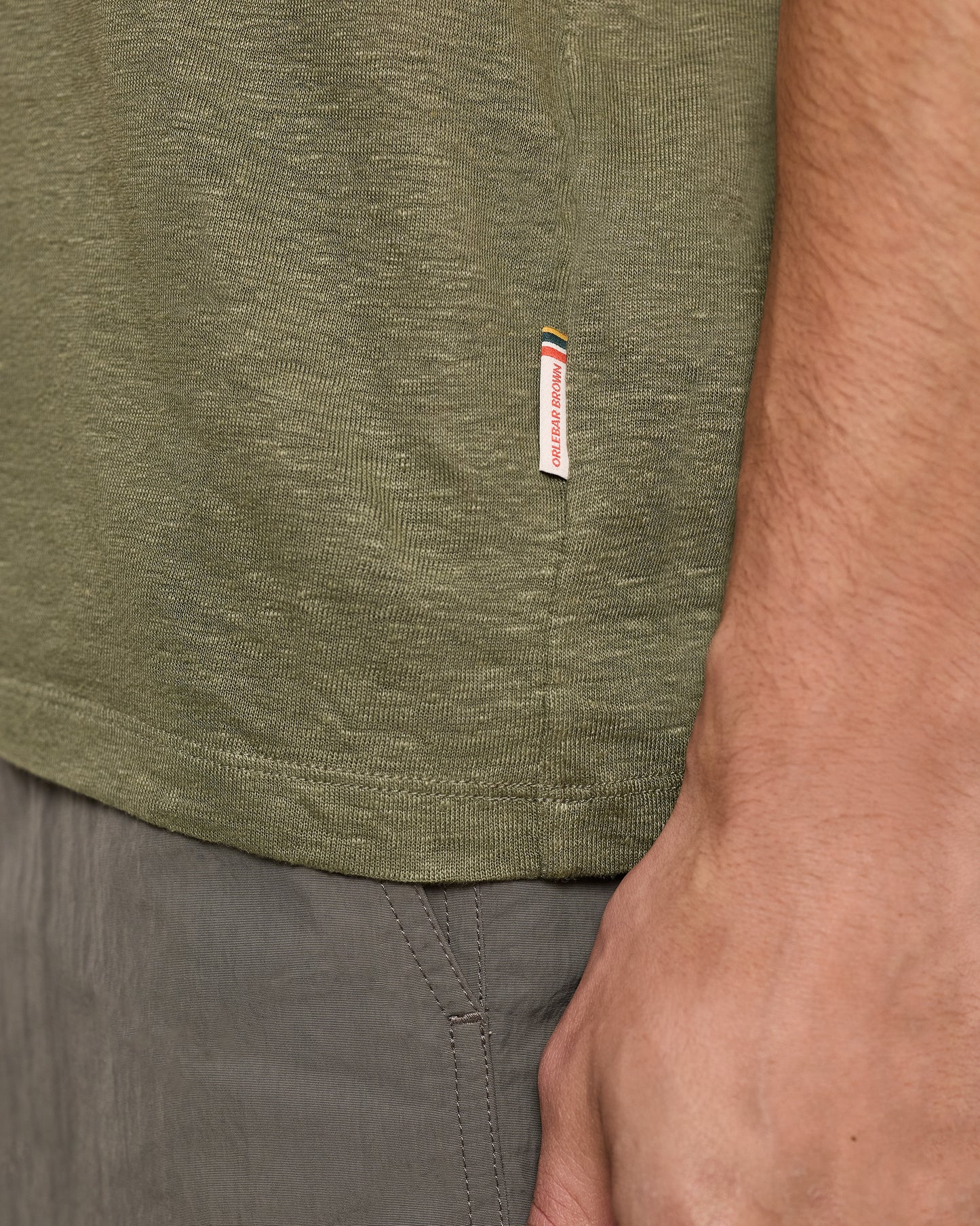 Close-up of a green t-shirt with a brand label and gray shorts.