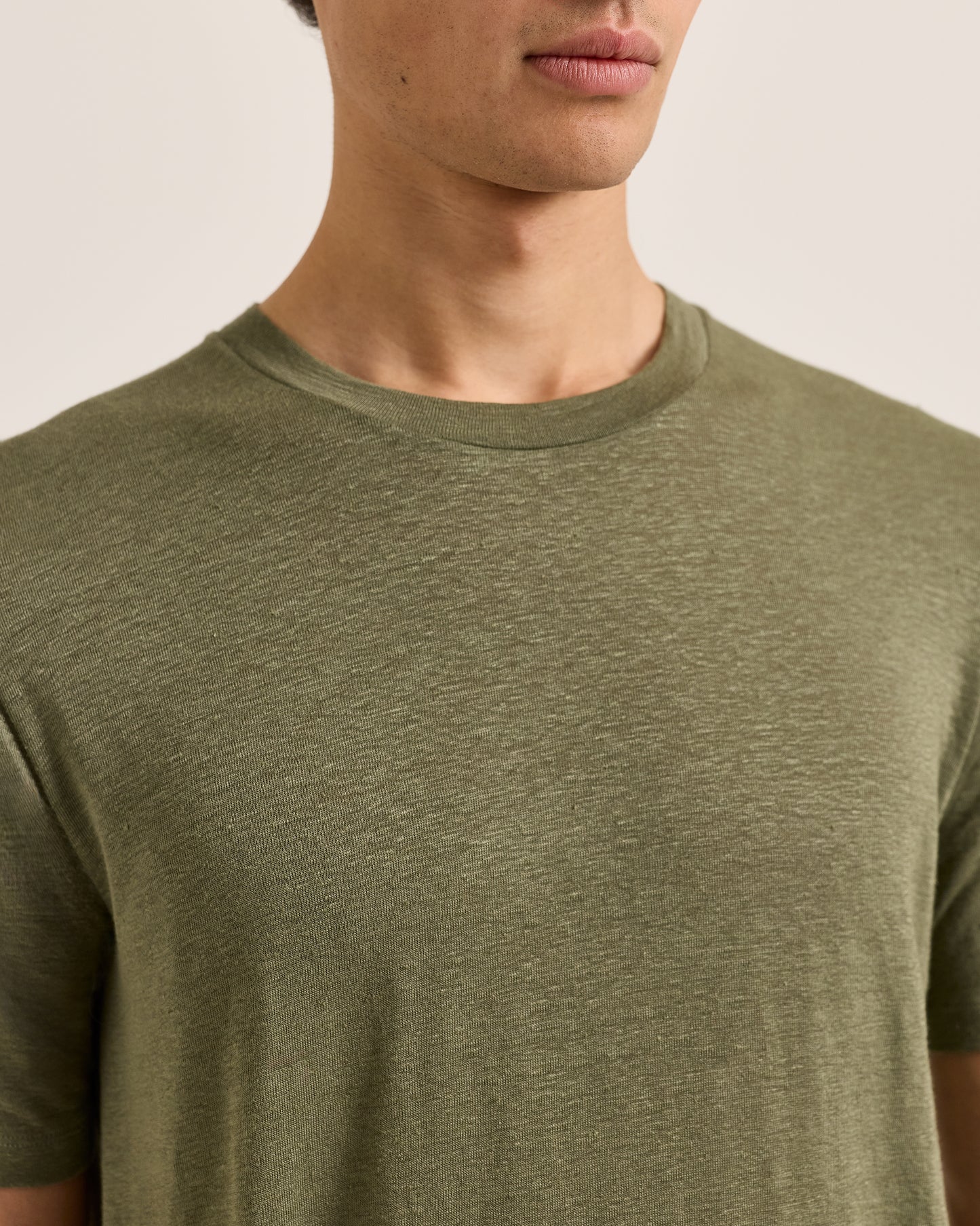 Person wearing a green t-shirt against a neutral background