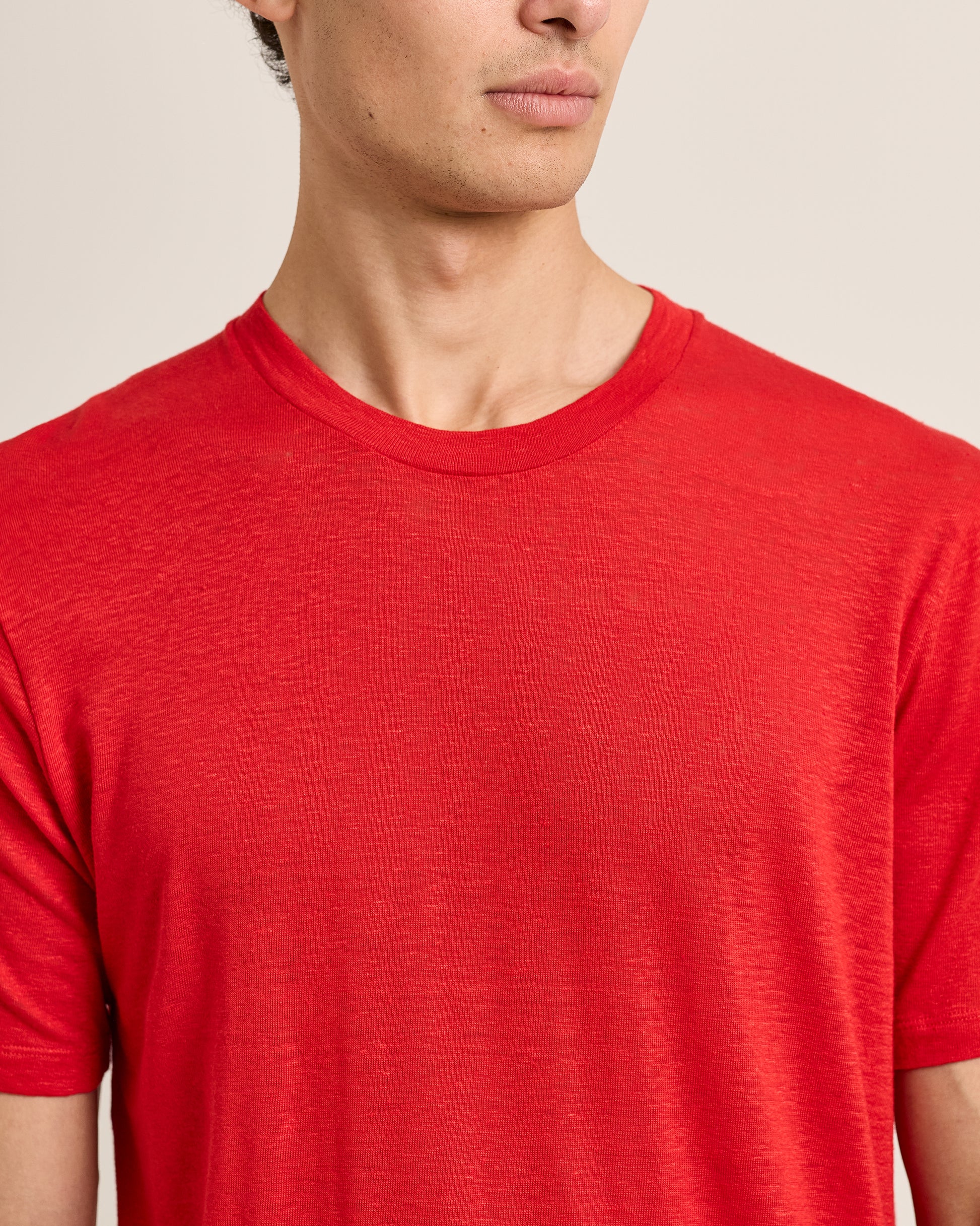 Person wearing a red t-shirt against a neutral background