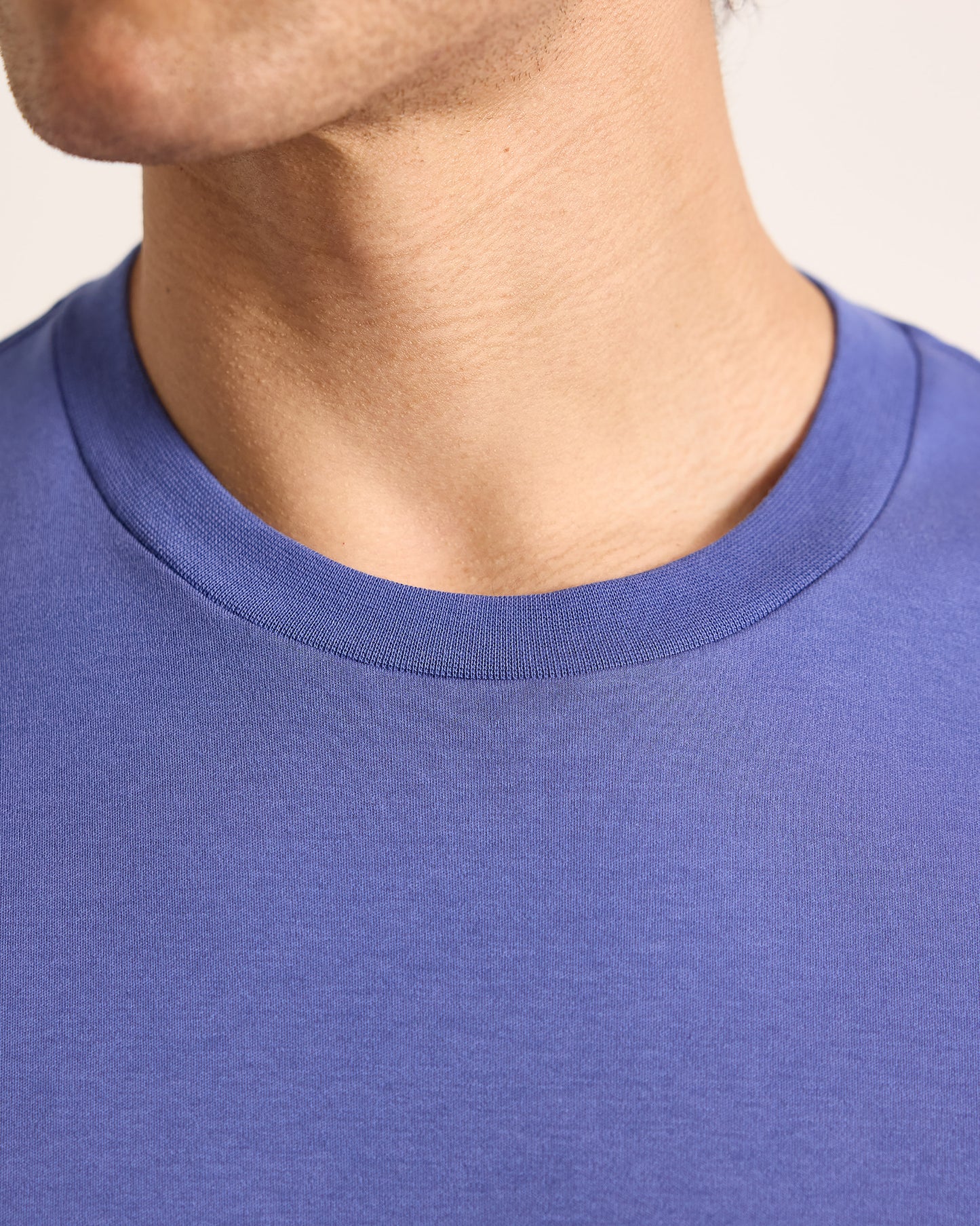 Close-up of a person wearing a blue shirt with a neutral background