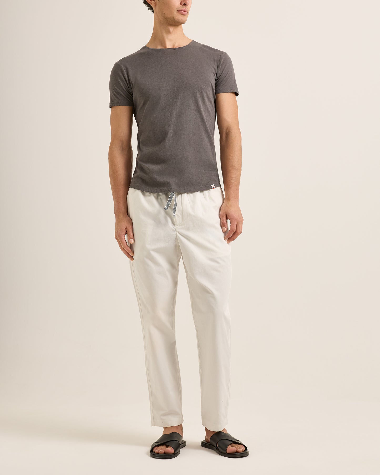 Person wearing a gray t-shirt and white pants on a plain background