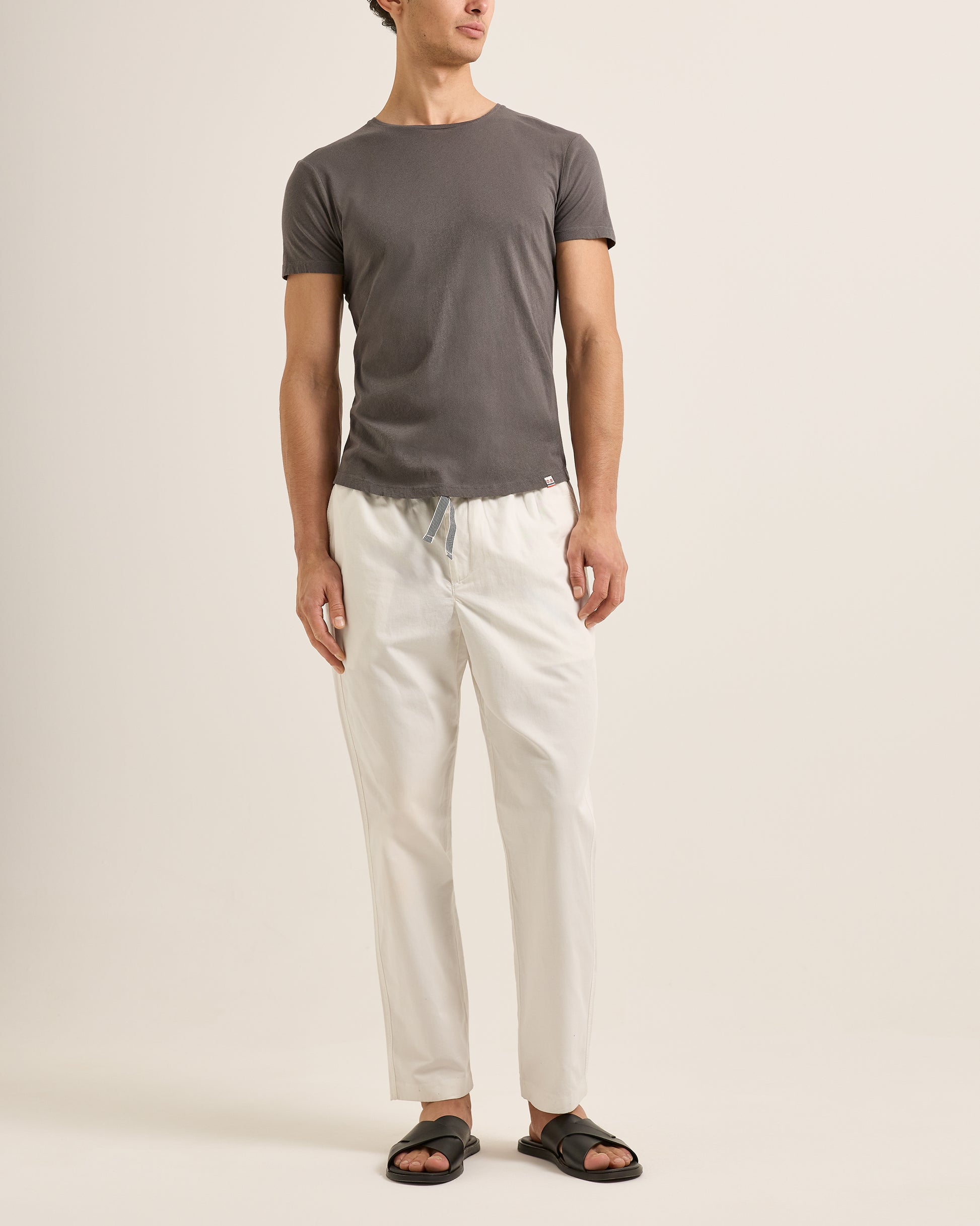 Person wearing a gray t-shirt and white pants on a plain background