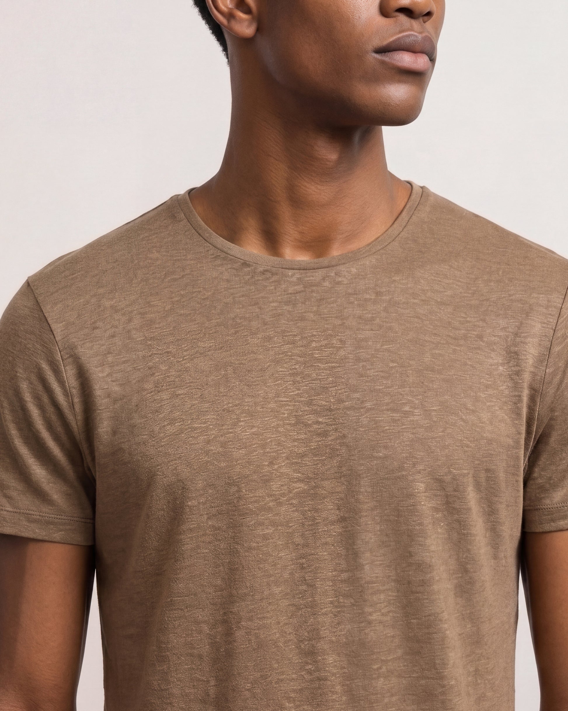 Man wearing a brown t-shirt against a plain background