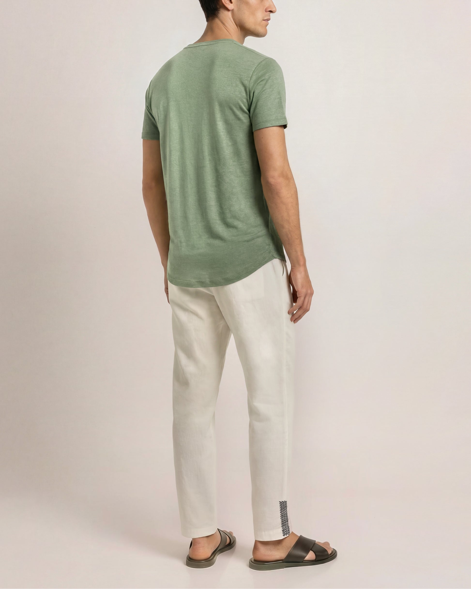 Man wearing a green t-shirt and white pants against a plain background