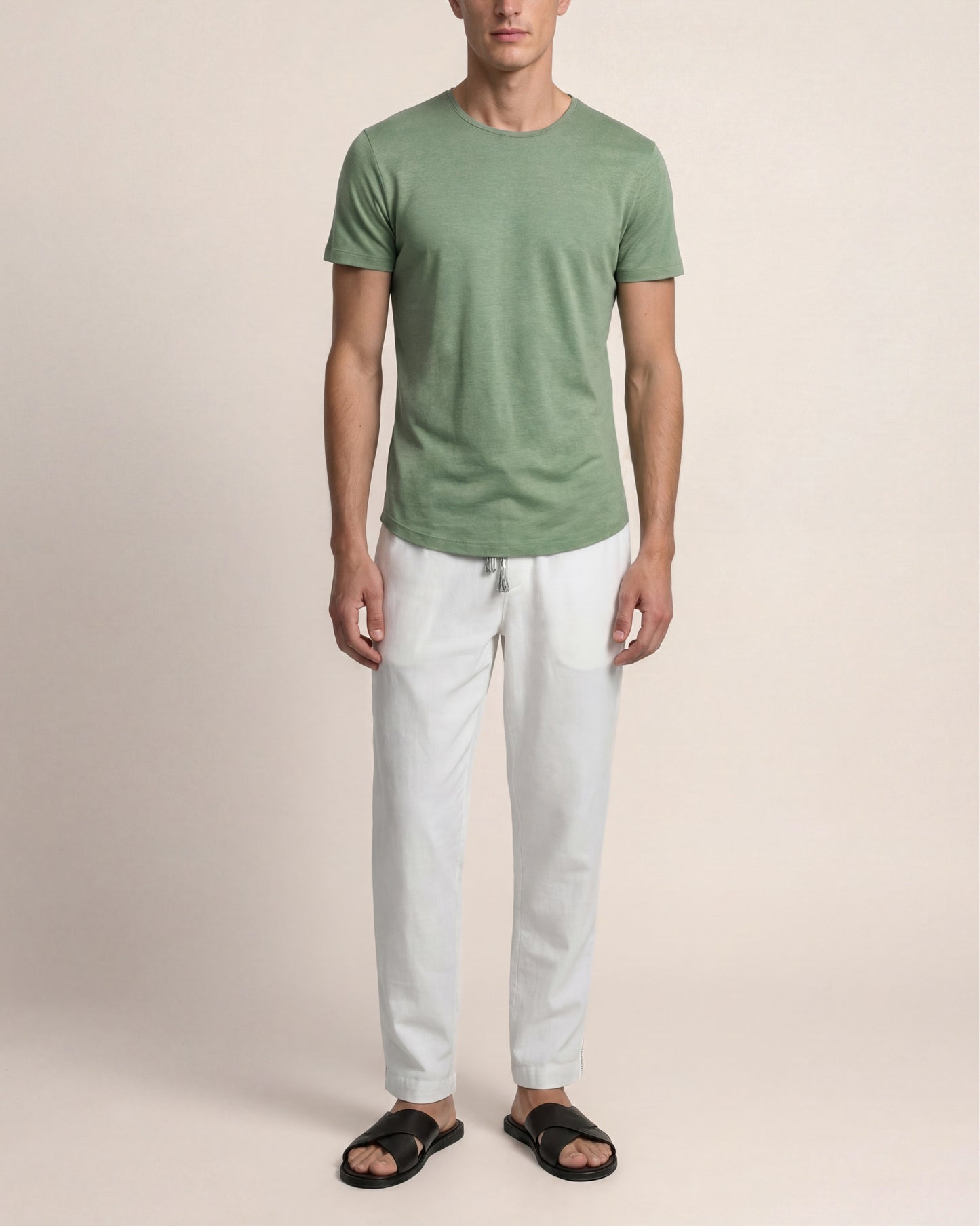 Man wearing a green t-shirt and white pants on a beige background