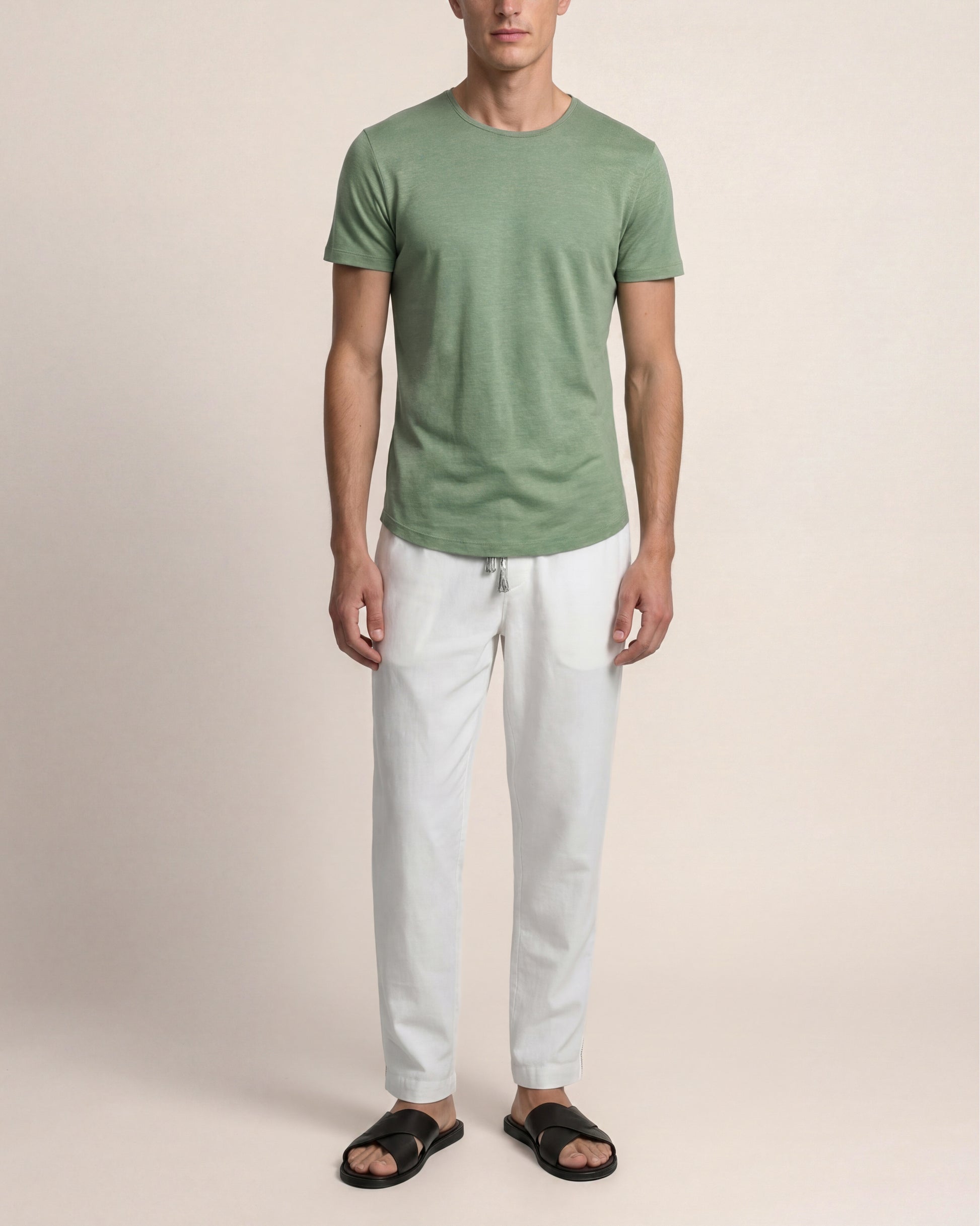 Man wearing a green t-shirt and white pants on a beige background