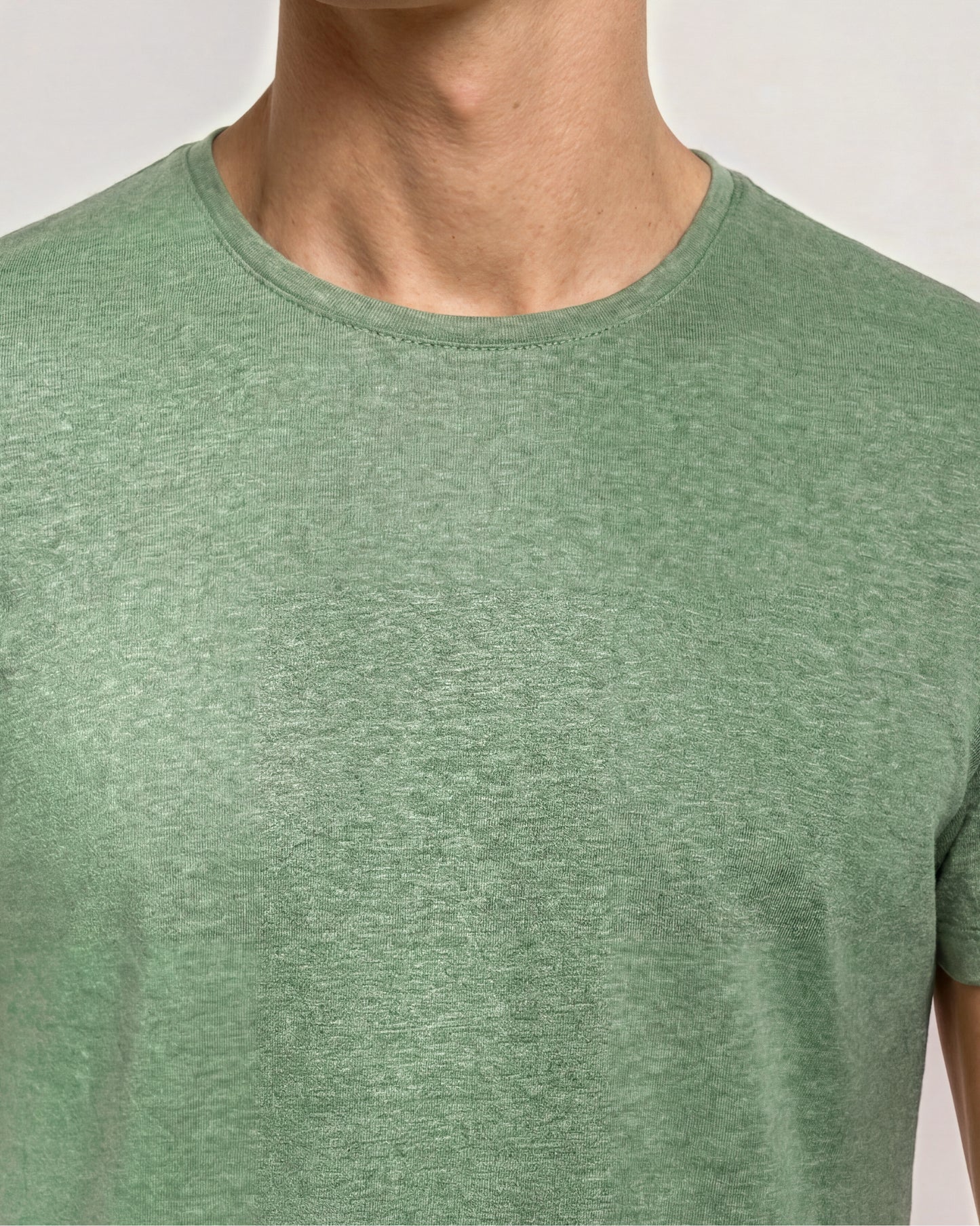 Green t-shirt worn by a person on a plain background