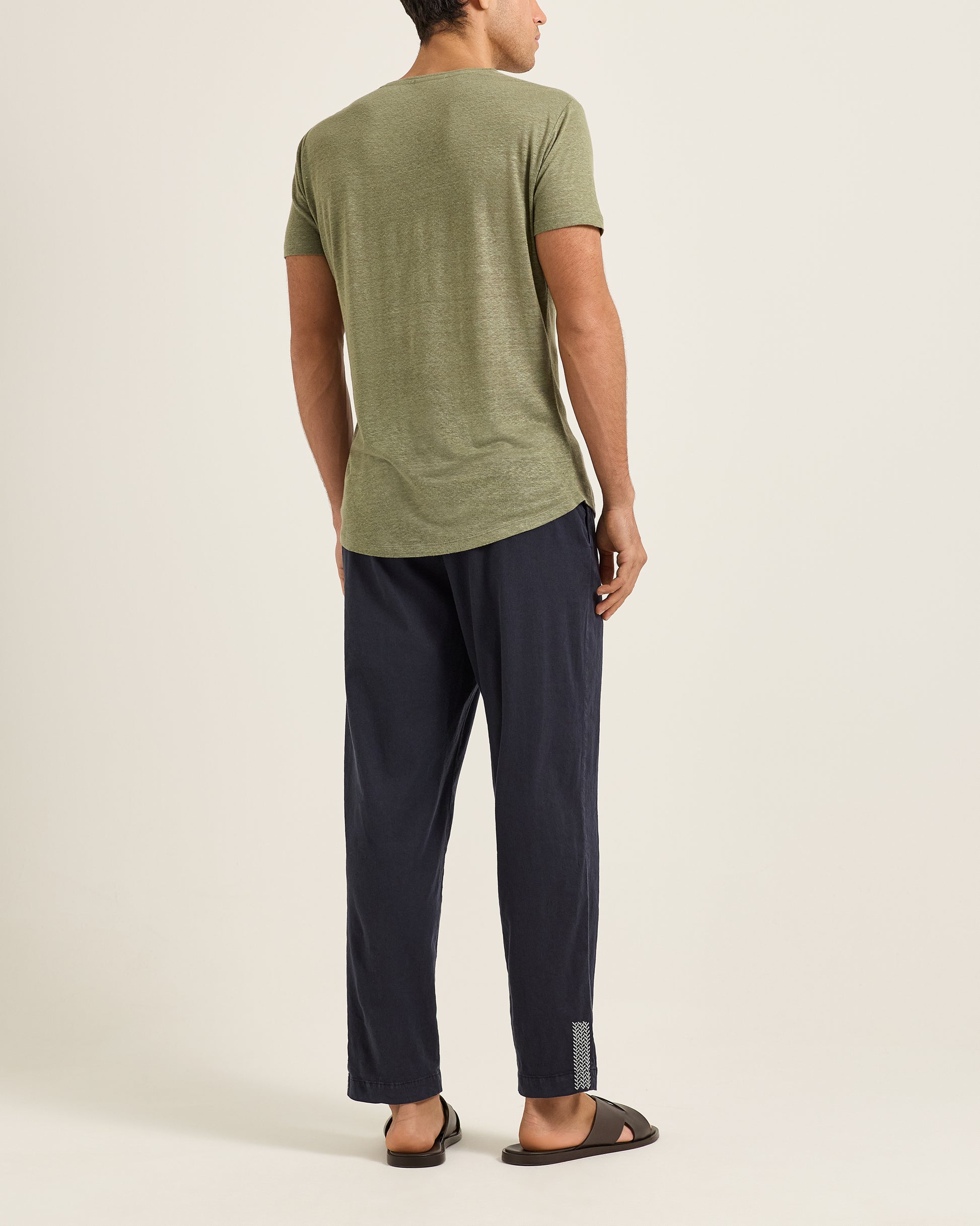 Person wearing a green t-shirt and navy pants on a white background