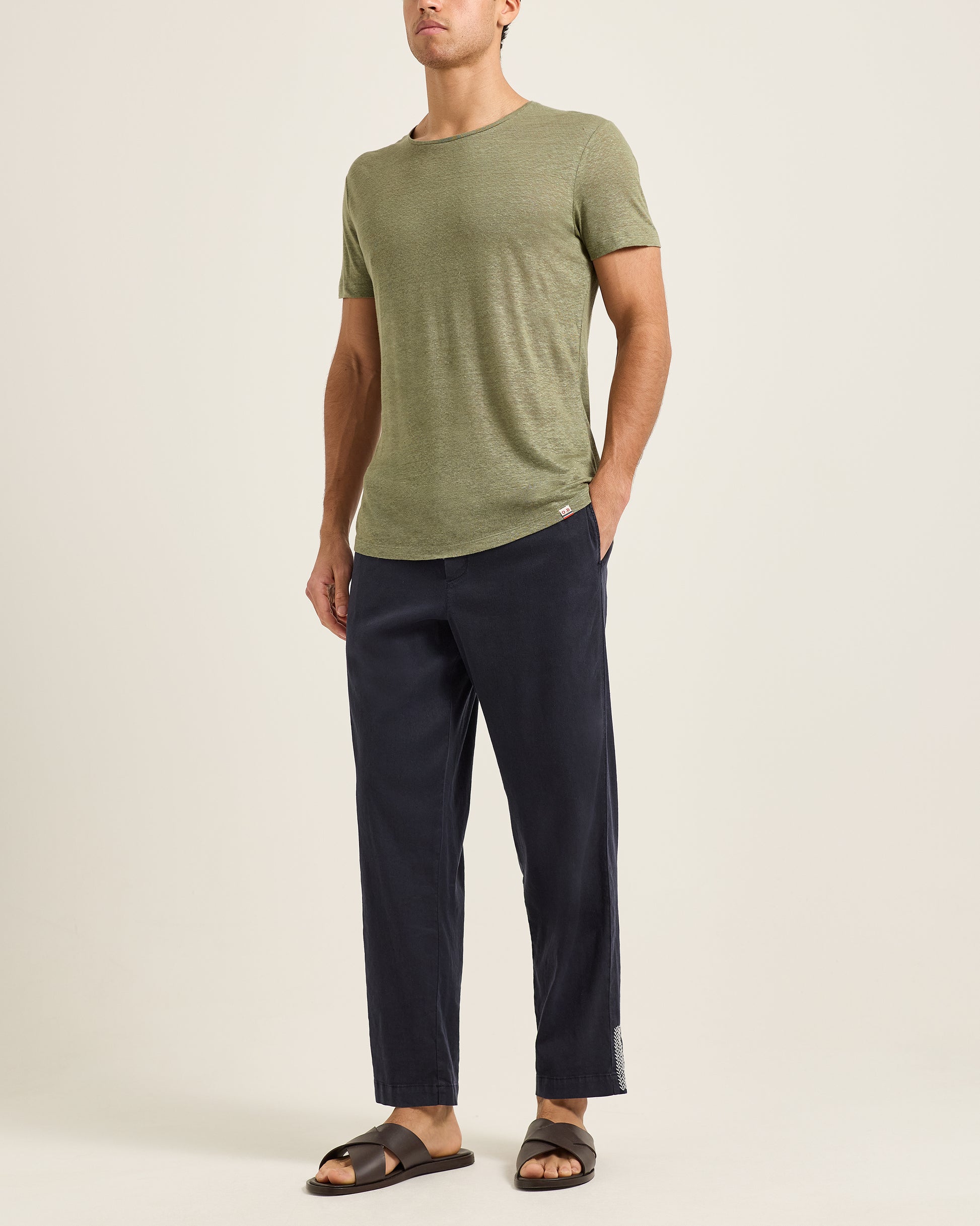 Person wearing a green t-shirt and navy pants on a plain background